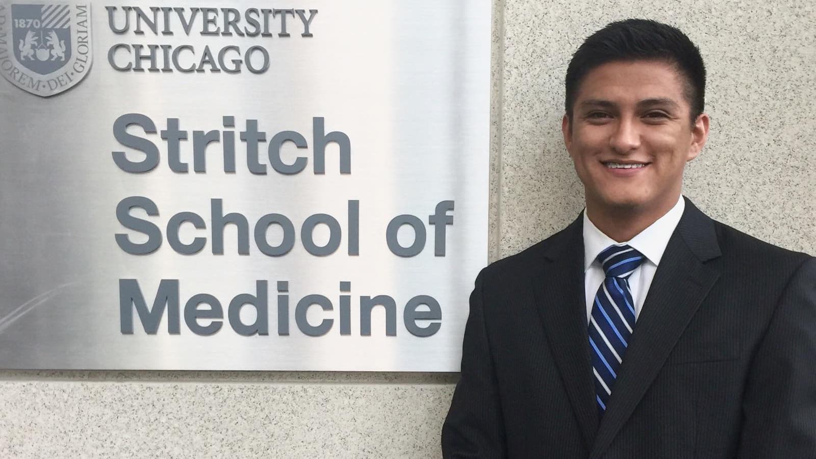Man in suit standing next to school sign
