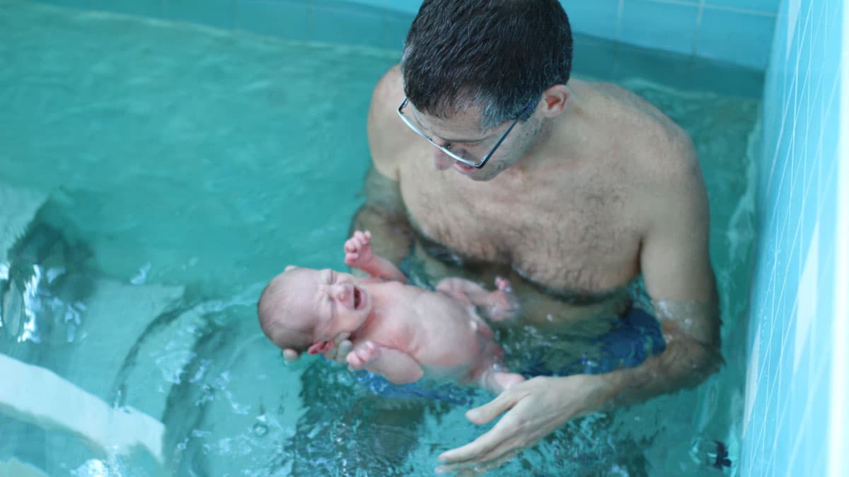 Amir Tal holds his newborn baby girl in a conversion ceremony in Portland, Oregon.