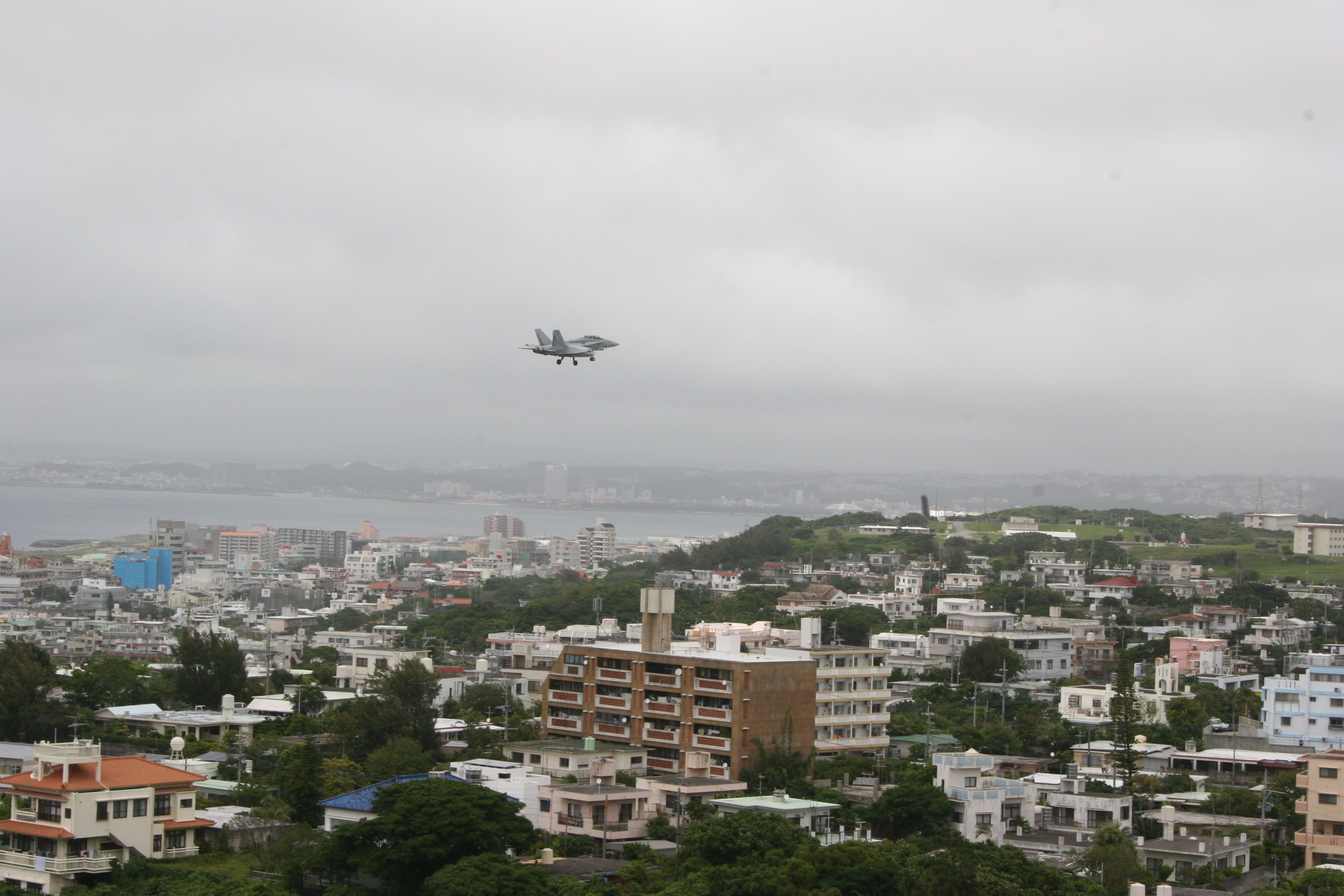 A US military aircraft prepares to land on a runway at the Futenma military base, adjacent to a densely populated city on Okinawa island.