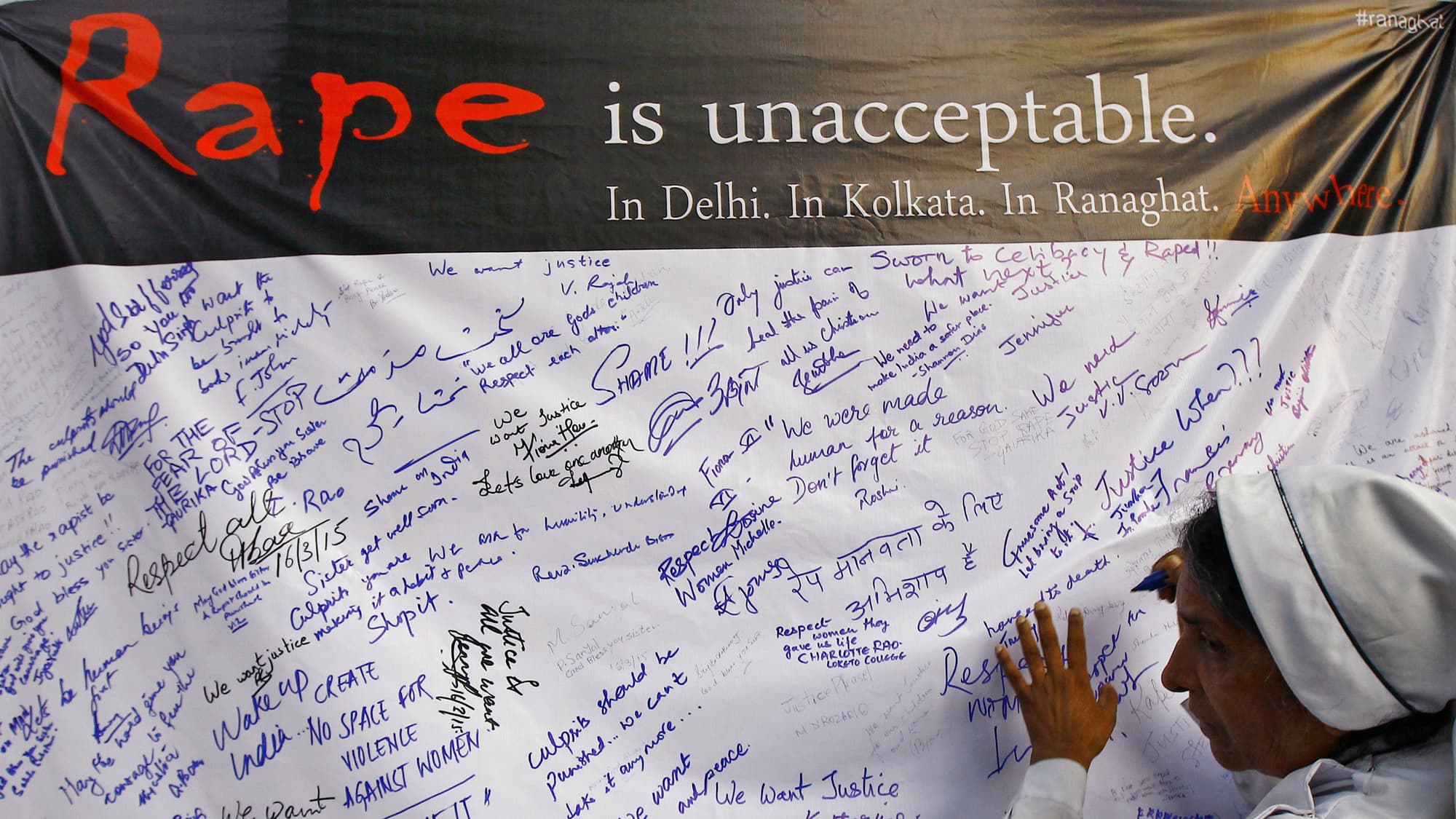 A Catholic nun signs a banner during a rally to show solidarity with a nun who was raped during an armed assault on a convent school, in Kolkata.