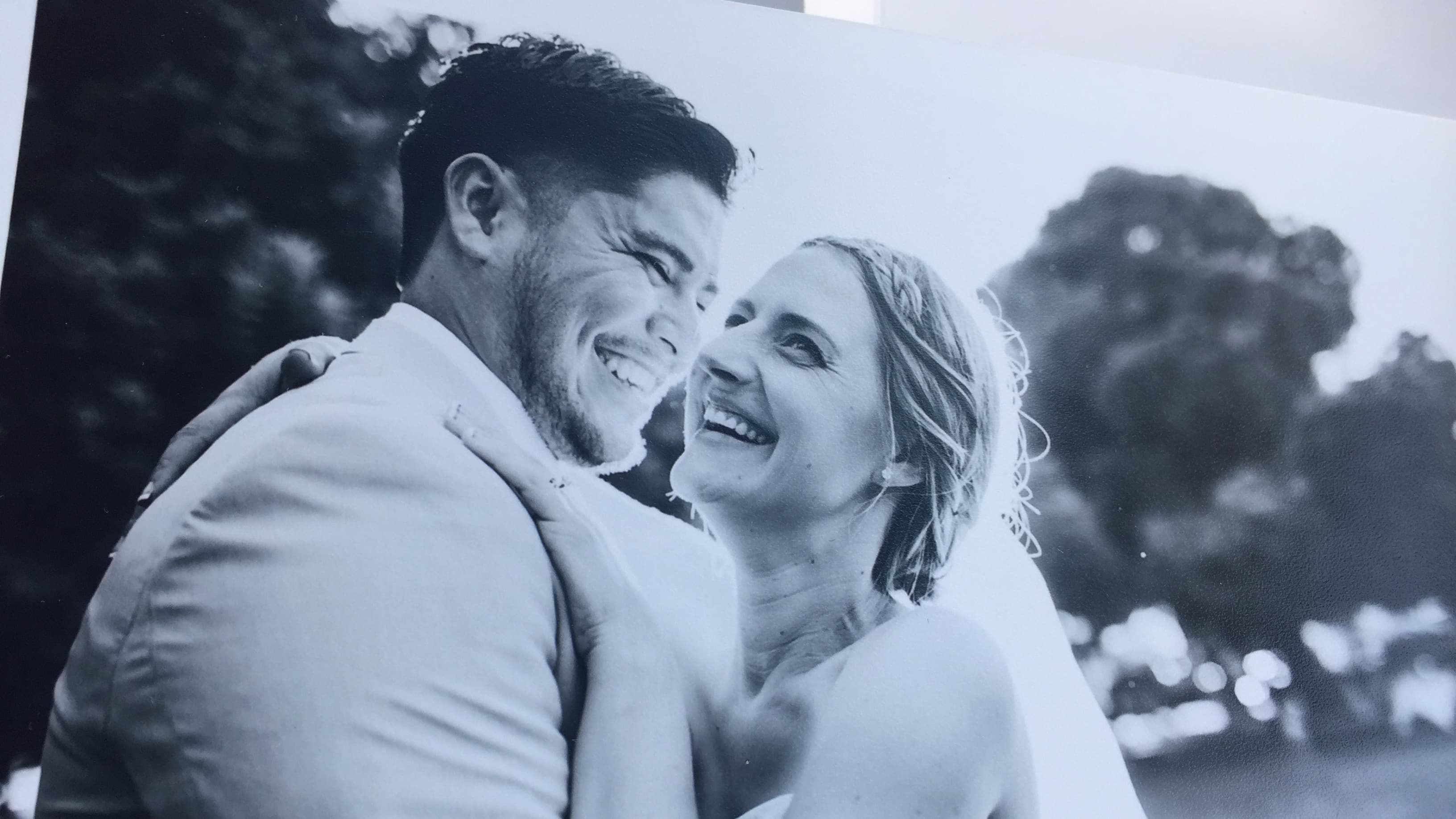 Photograph of a black and white wedding photo, bride laughing in groom's arms