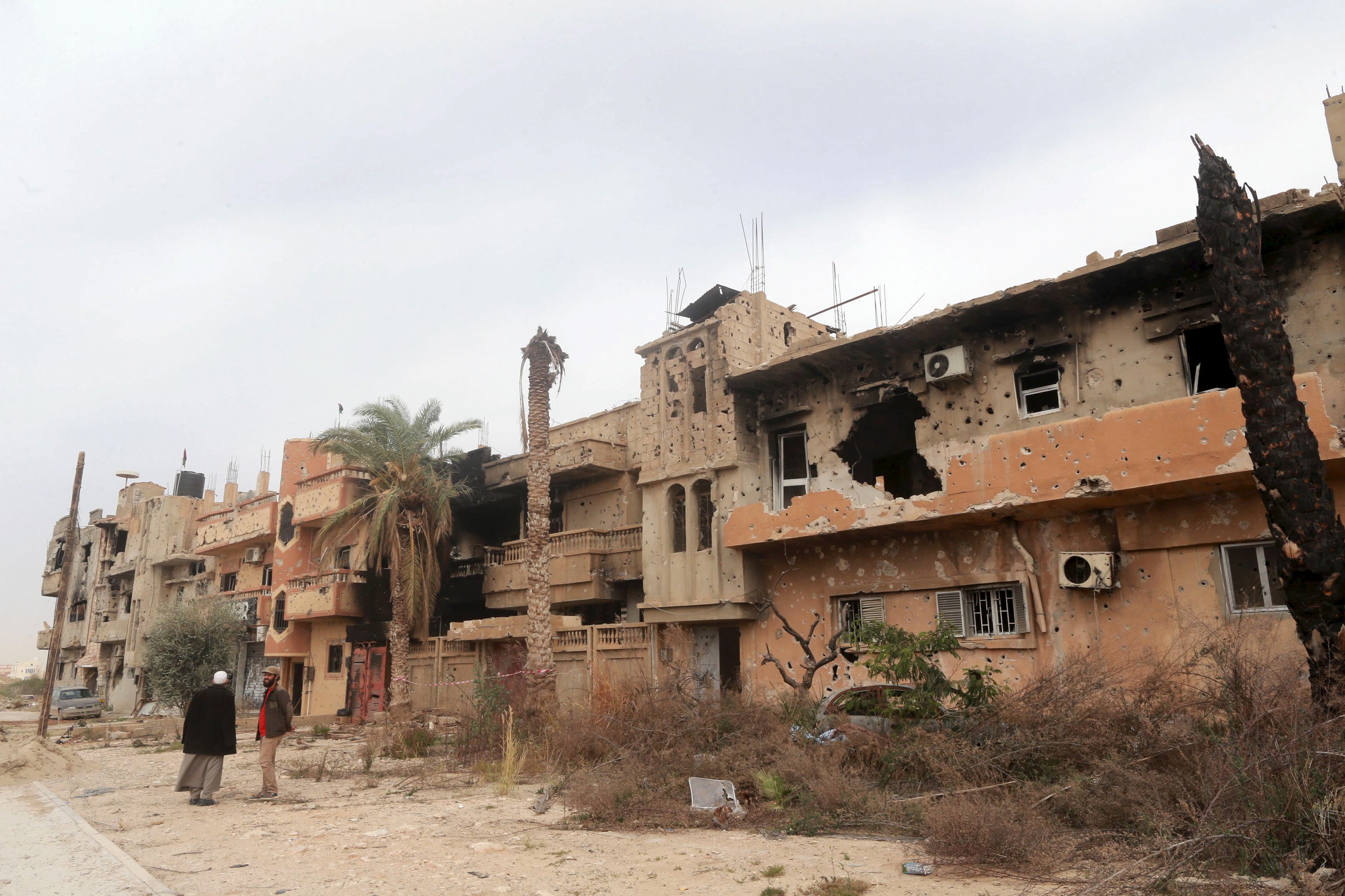 Two men stand next to destroyed buildings after clashes between military forces loyal to Libya's eastern government and Islamist fighters, in Benghazi, Libya, February 28, 2016.