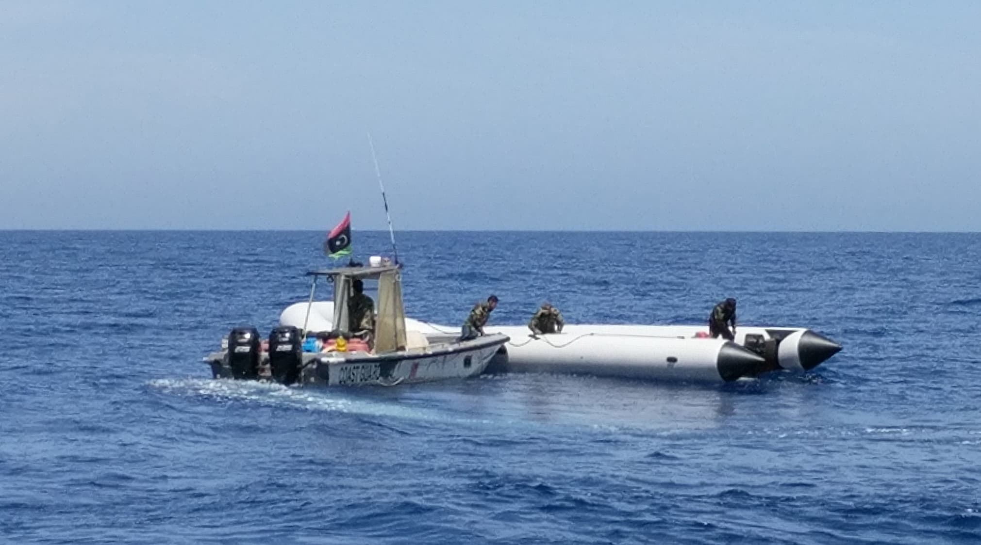 The Libyan coast guard boards a boat in the Mediterranean while humanitarian groups bring migrants onto their ships.