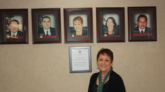 Former farmworker and current Delano Mayor, Grace Vallejo, stands in front of photos of her fellow city council members. The city council is made up of all Hispanic members. "That's a huge change from back in the 1960s. We've come a long way." she says. V