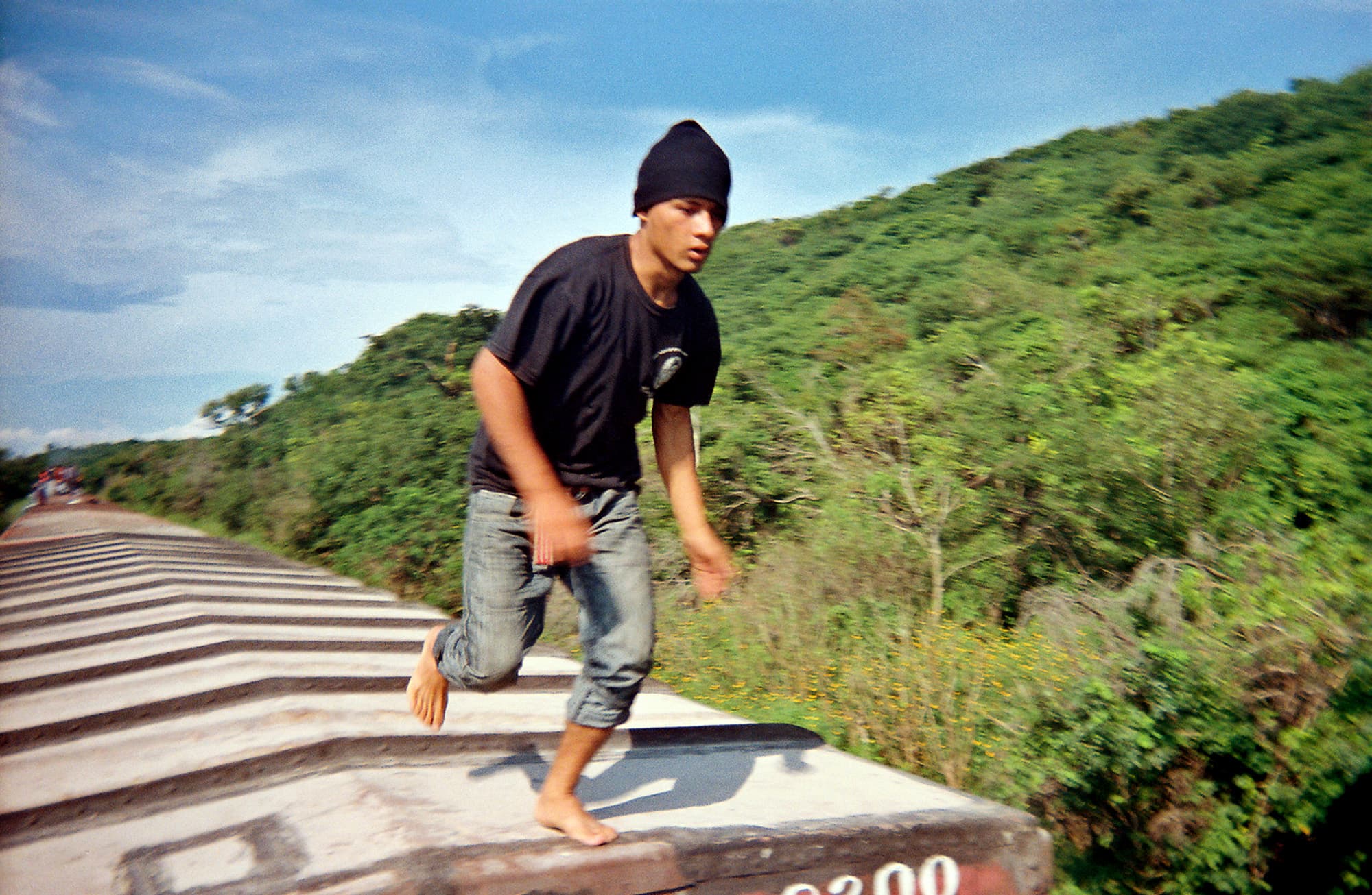 “It’s just crazy to see this guy barefoot,” says Pindado. “The tops of the trains are so hot. At the same time, he’s wearing a hat. The temperatures drop at night, especially up north. You can also see that the train is moving and that he’s jumping. There