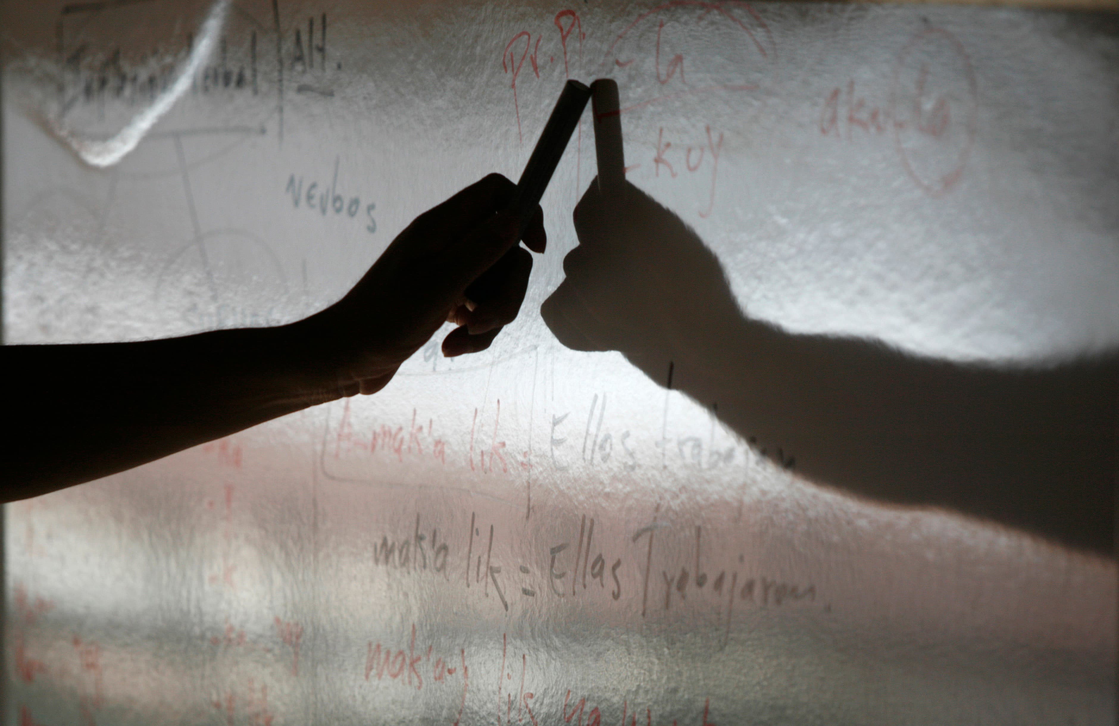 A teacher writes words from an indigenous language on a chalk board