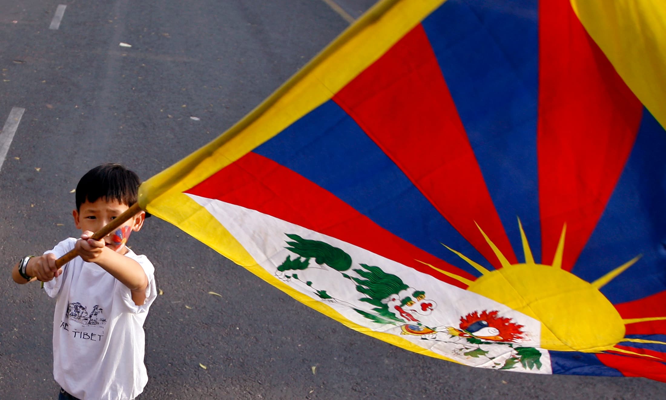 Young boy holds Tibet flag at independence protest.