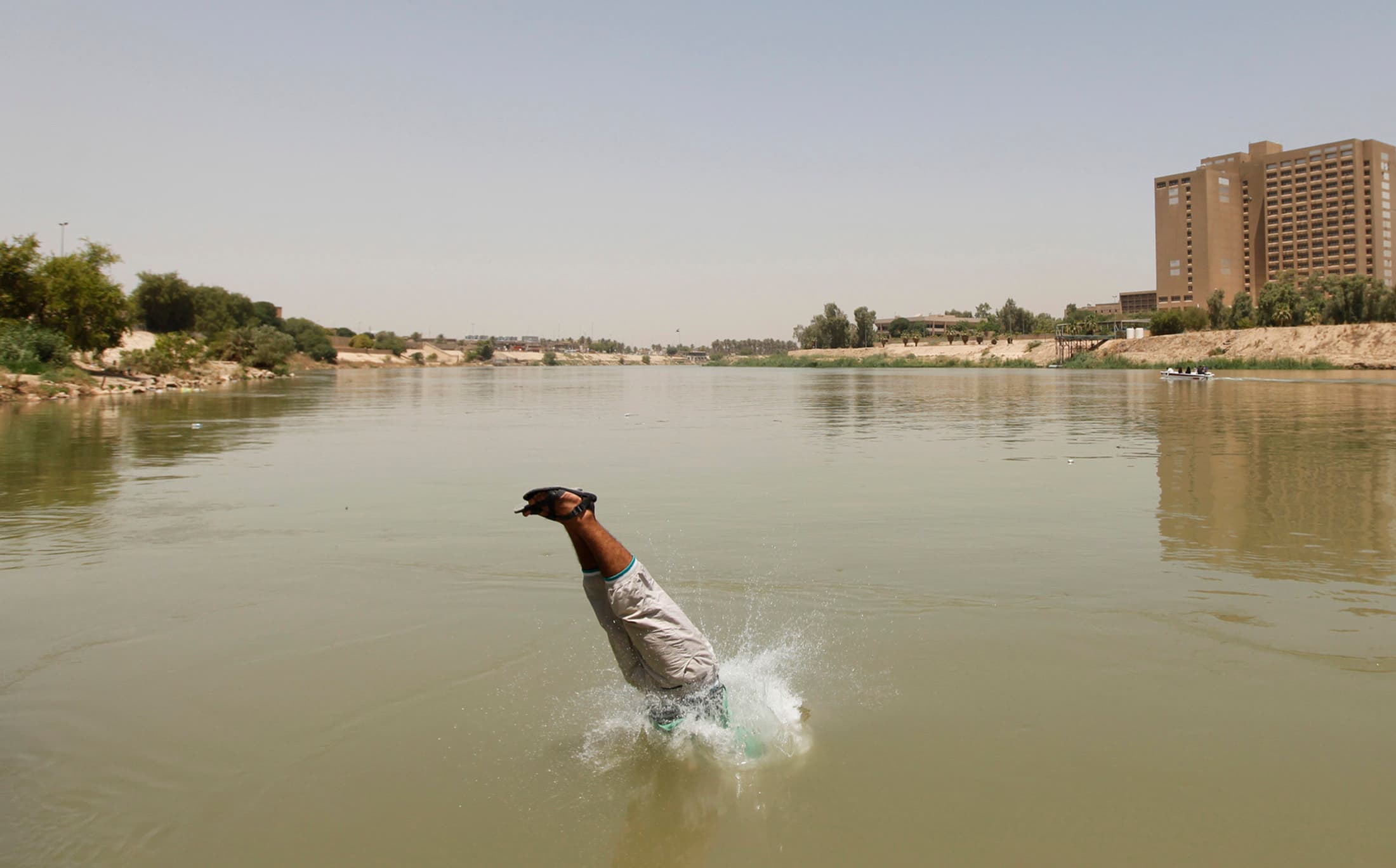 A Bagdad resident plunges into the Tigris river, sandals and all.