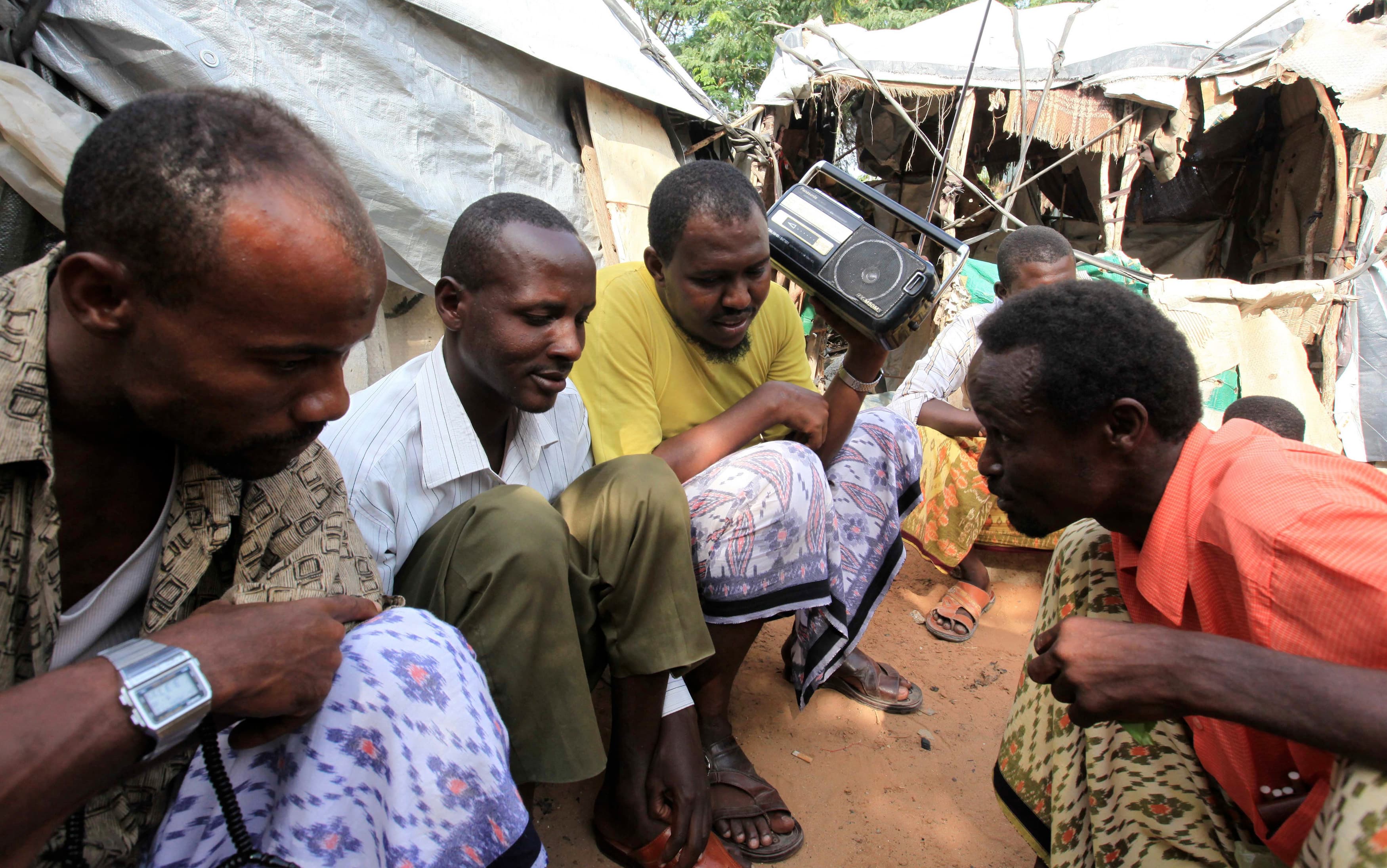 Internally displaced people Somalians gather outside their makeshift shelters in the Hodan district in southern Mogadishu to listen to proceeding of a 2012 parliamentary election.