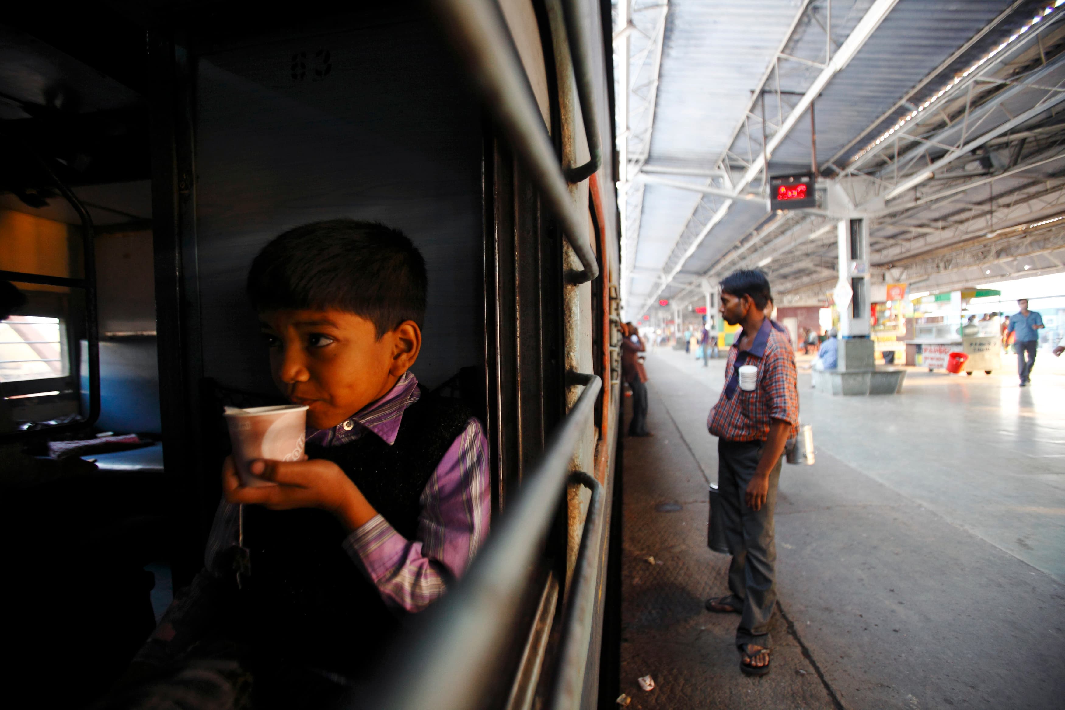 A young boy drinks tea in the early morning inside a train at Agra Cantt Railway Station in Agra, India.