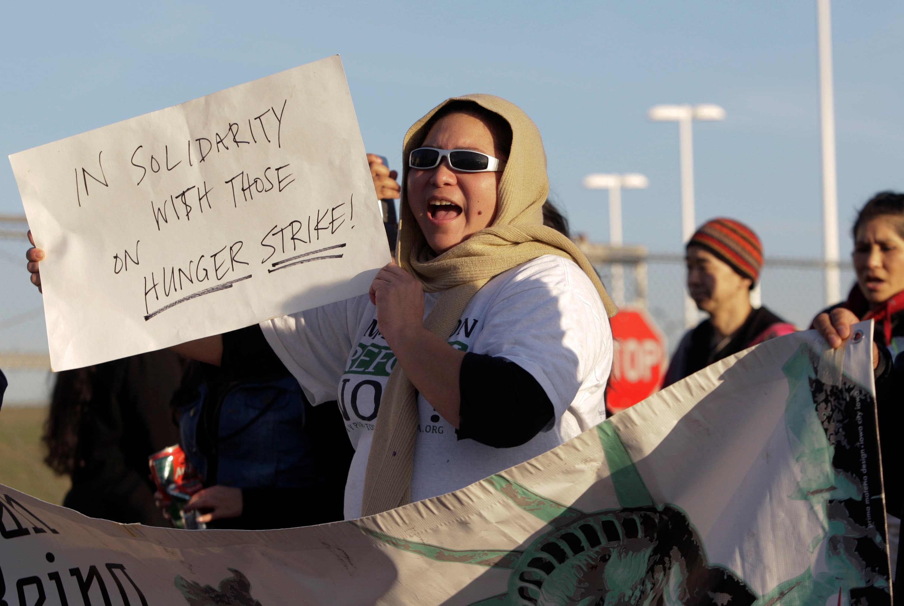 Woman holds up sign that readers "In solidarity with those on hunger strike"