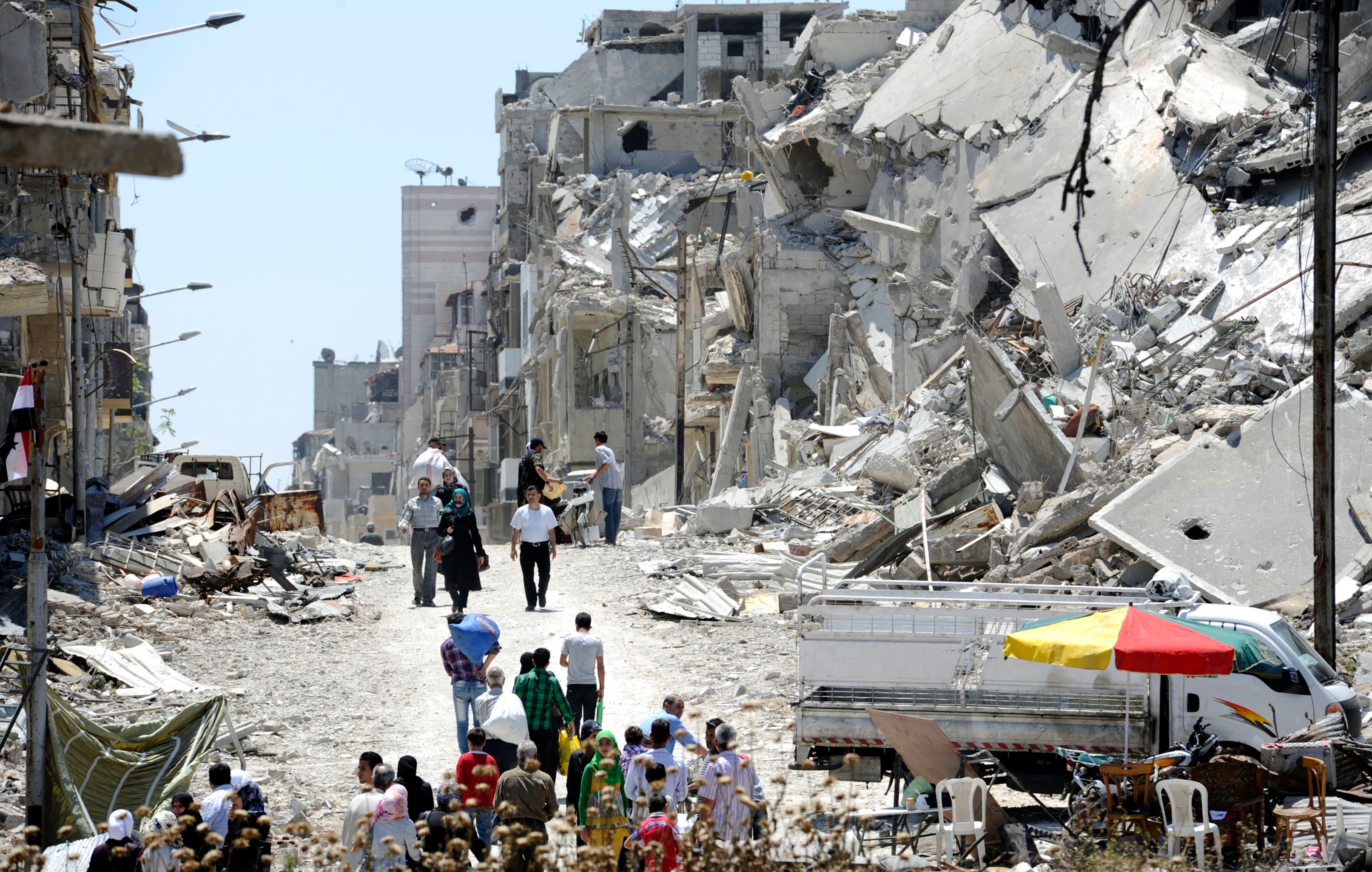 Residents arrive on foot to inspect their homes in the Wadi Al-Sayeh district of Homs, May 14th 2014.