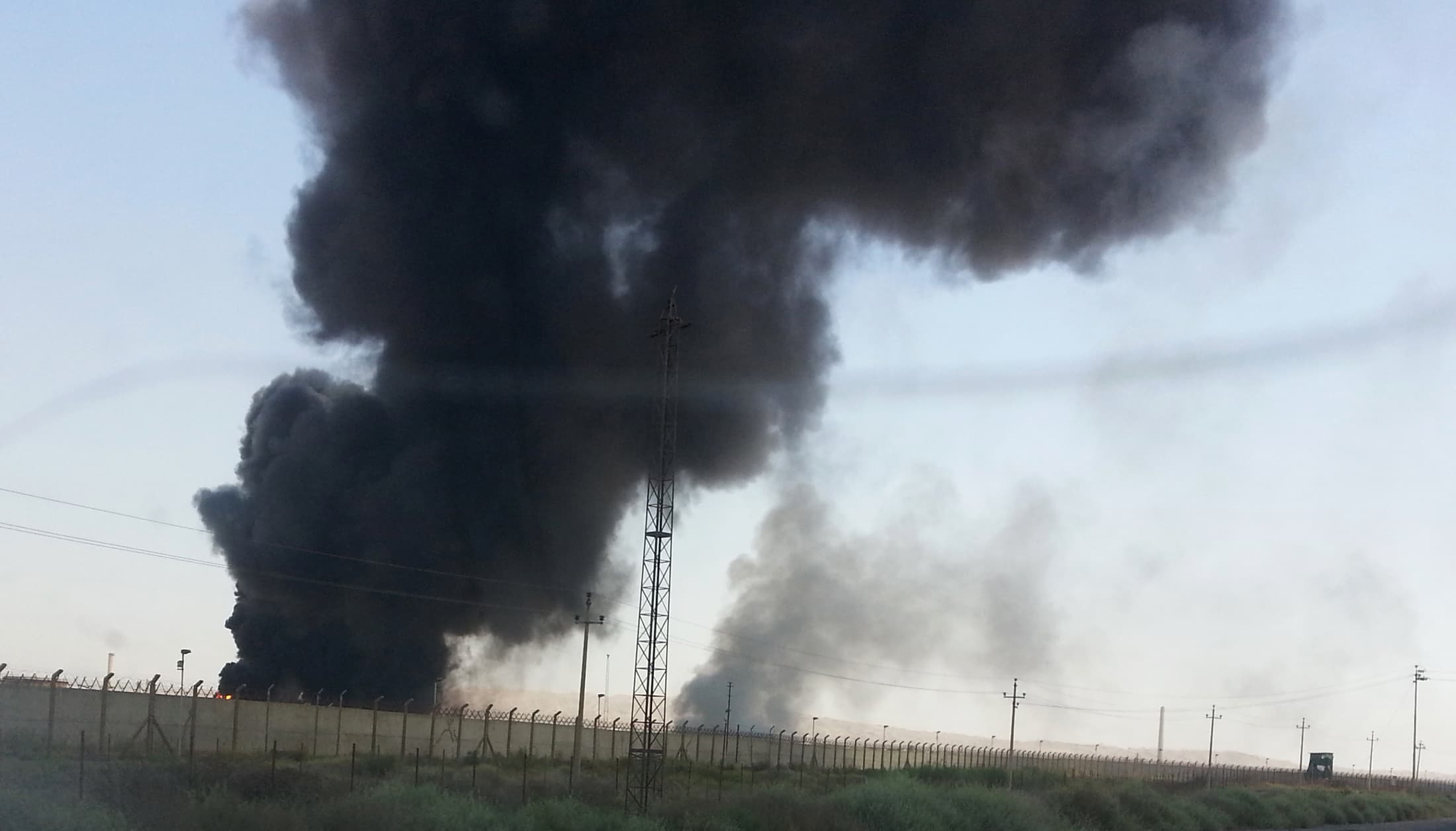 Smoke rises from a oil refinery in Baiji, north of Baghdad, in this picture taken through the windscreen of a car, June 19, 2014. Iraqi government forces battled Sunni rebels for control of the country's biggest refinery on Thursday as Prime Minister Nuri