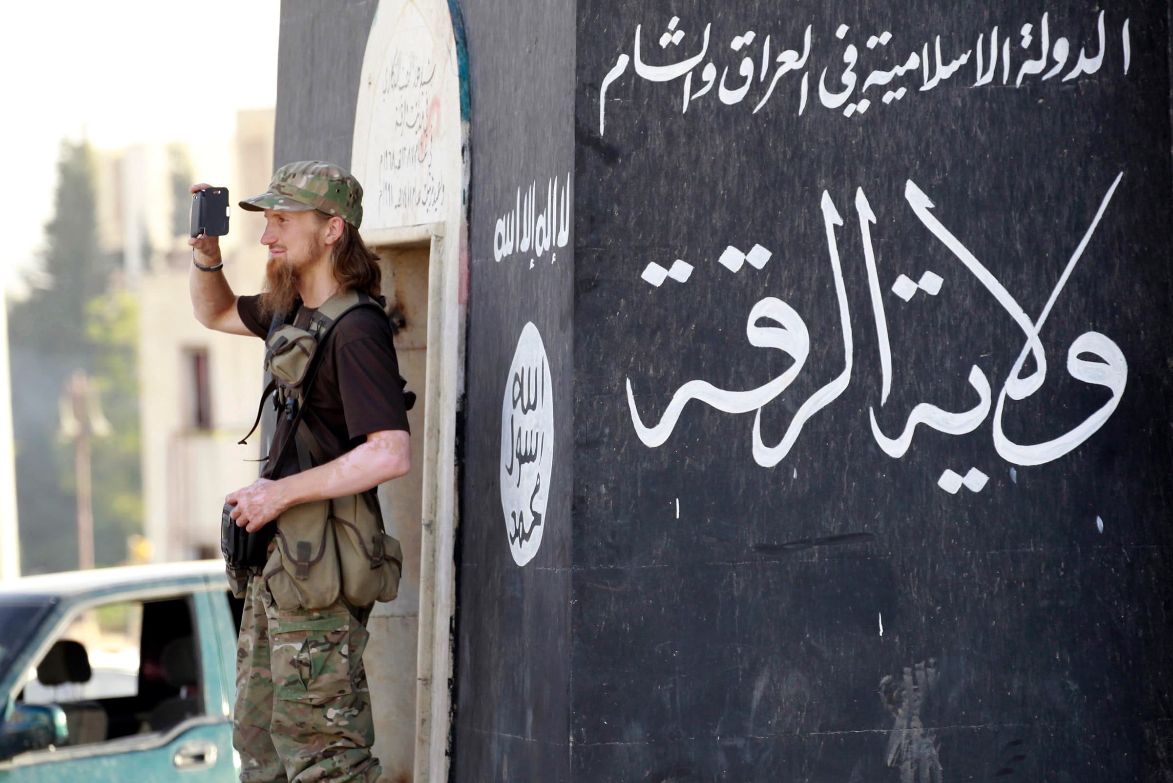 A militant Islamist fighter uses a mobile to film his fellow fighters taking part in a military parade along the streets of Syria's northern Raqqa province on June 30, 2014.