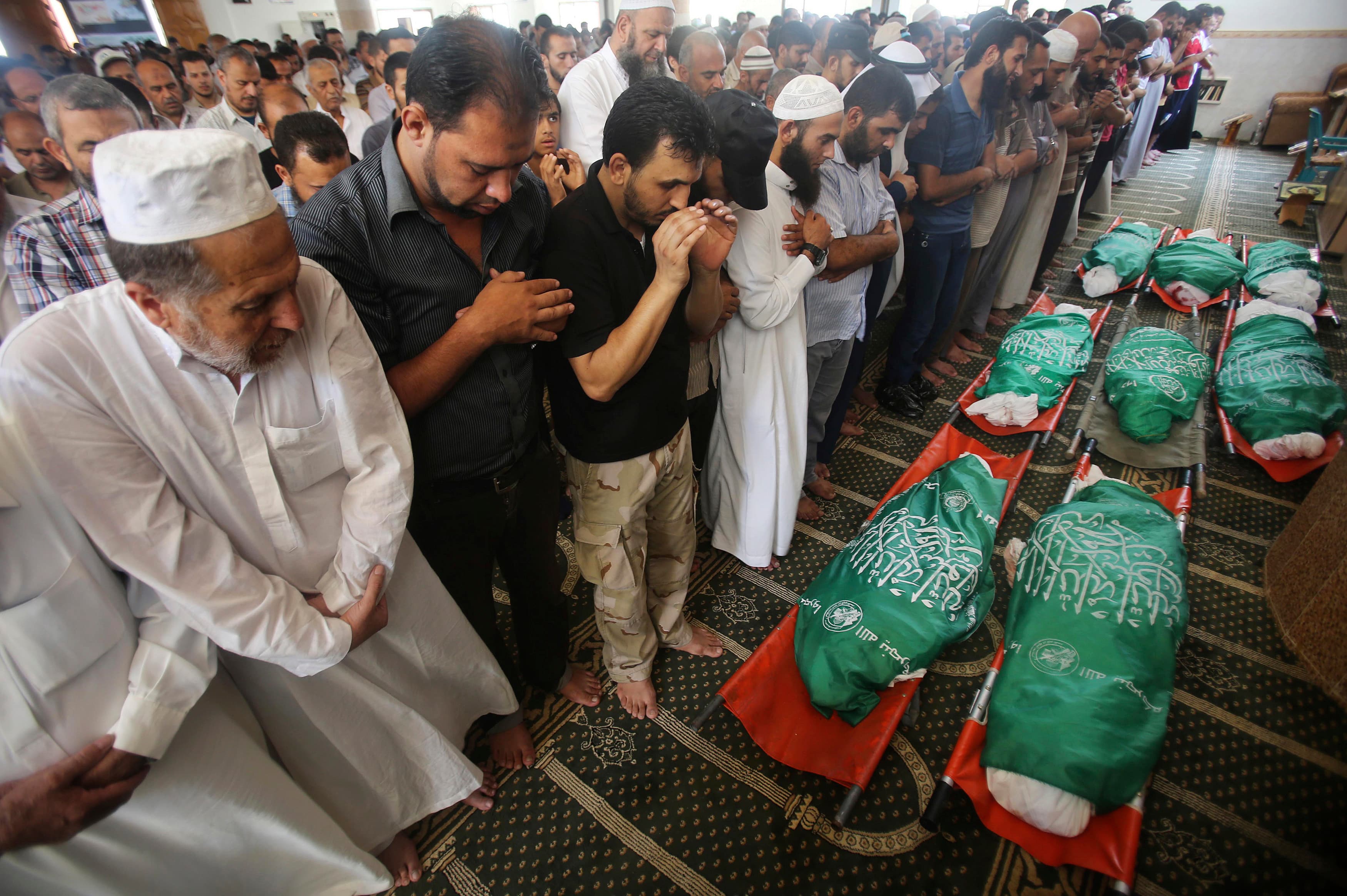 People pray next to the bodies of eight Palestinian members from the al-Haj family from Khan Younis in the southern Gaza Strip. Palestinian medics said the relatives were killed in an early morning air strike carried out by Israel that destroyed at least