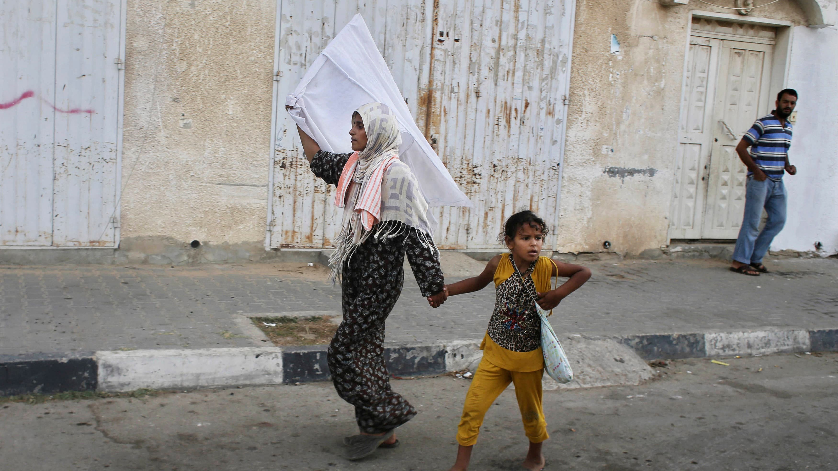 A Palestinian woman waves a white flag of surrender after an Israeli shelling in Gaza.