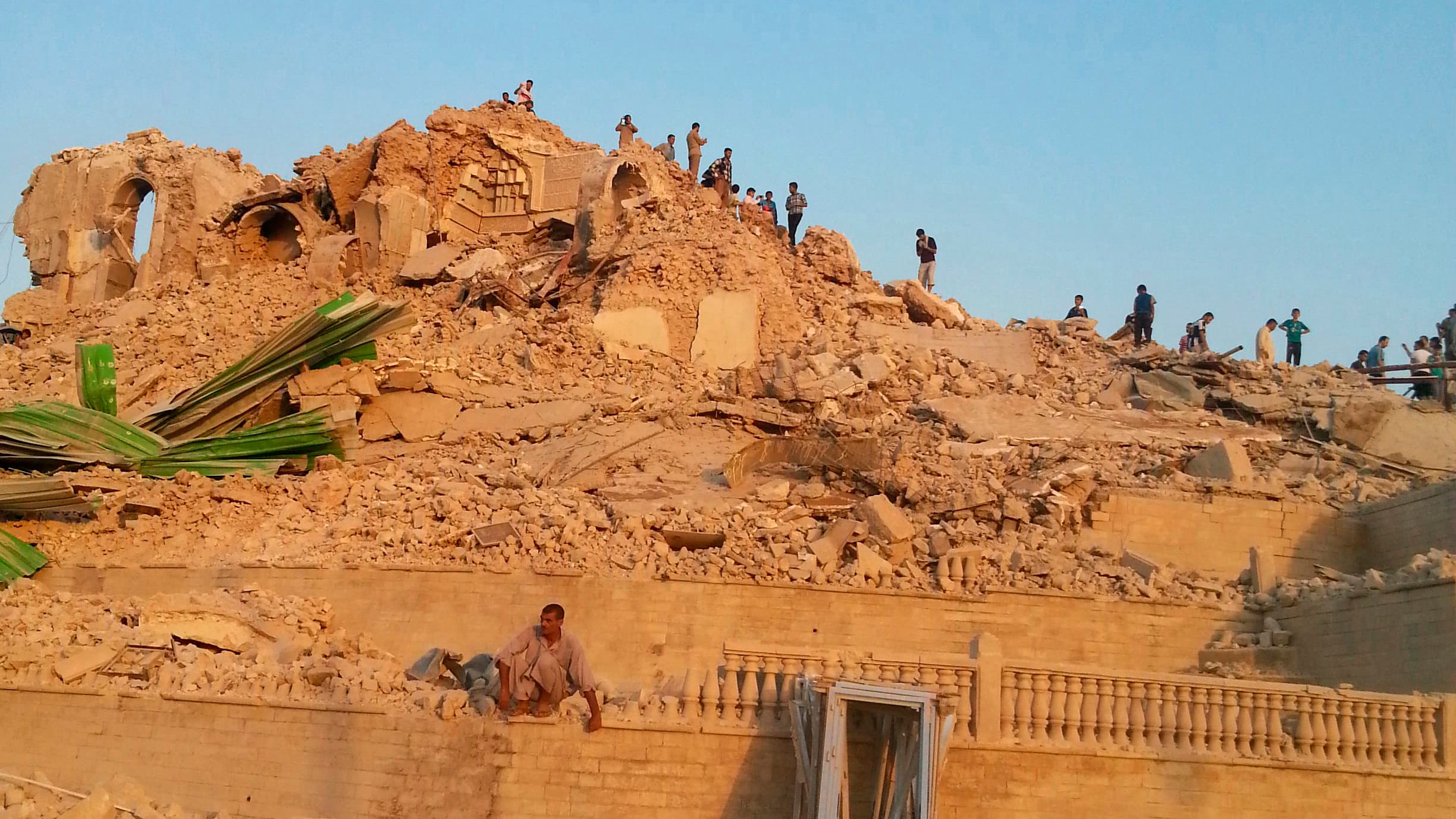 People walk through the rubble of the Prophet Younis Mosque after it was destroyed in a bomb attack by militants from ISIS in the city of Mosul on July 24, 2014.