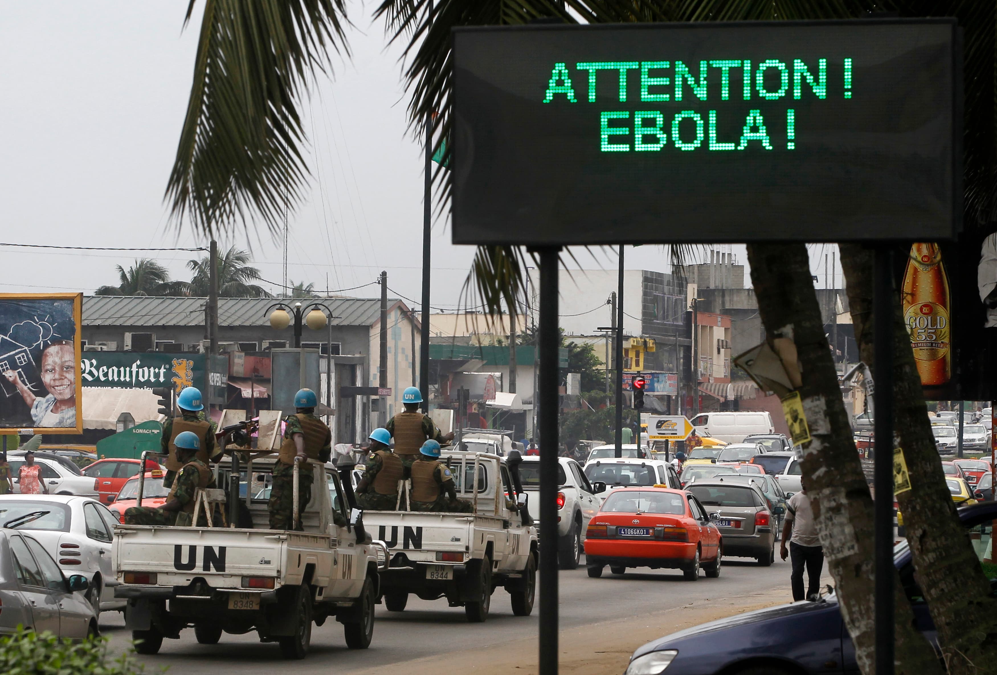 A UN convoy of soldiers passes a screen displaying a message about Ebola on a street in Abidjan, Ivory Coast, on August 14, 2014.