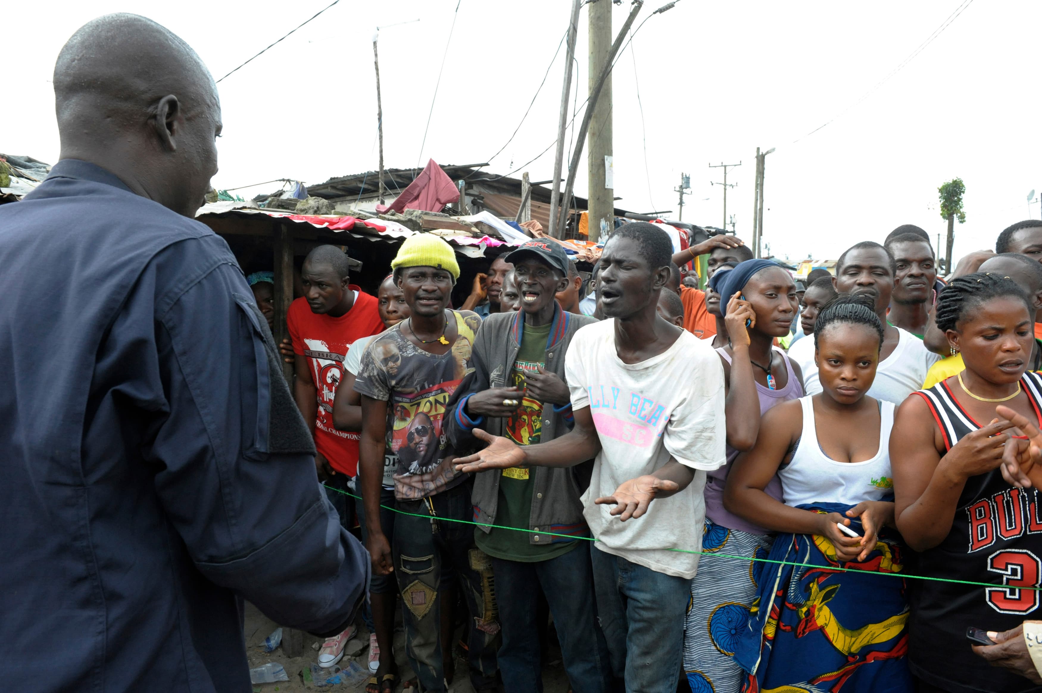 Residents in an Ebola quarantine area in the West Point of Monrovia, Liberia, complain to a security officer as they wait for their relatives to bring them food and essentials on August 23, 2014.