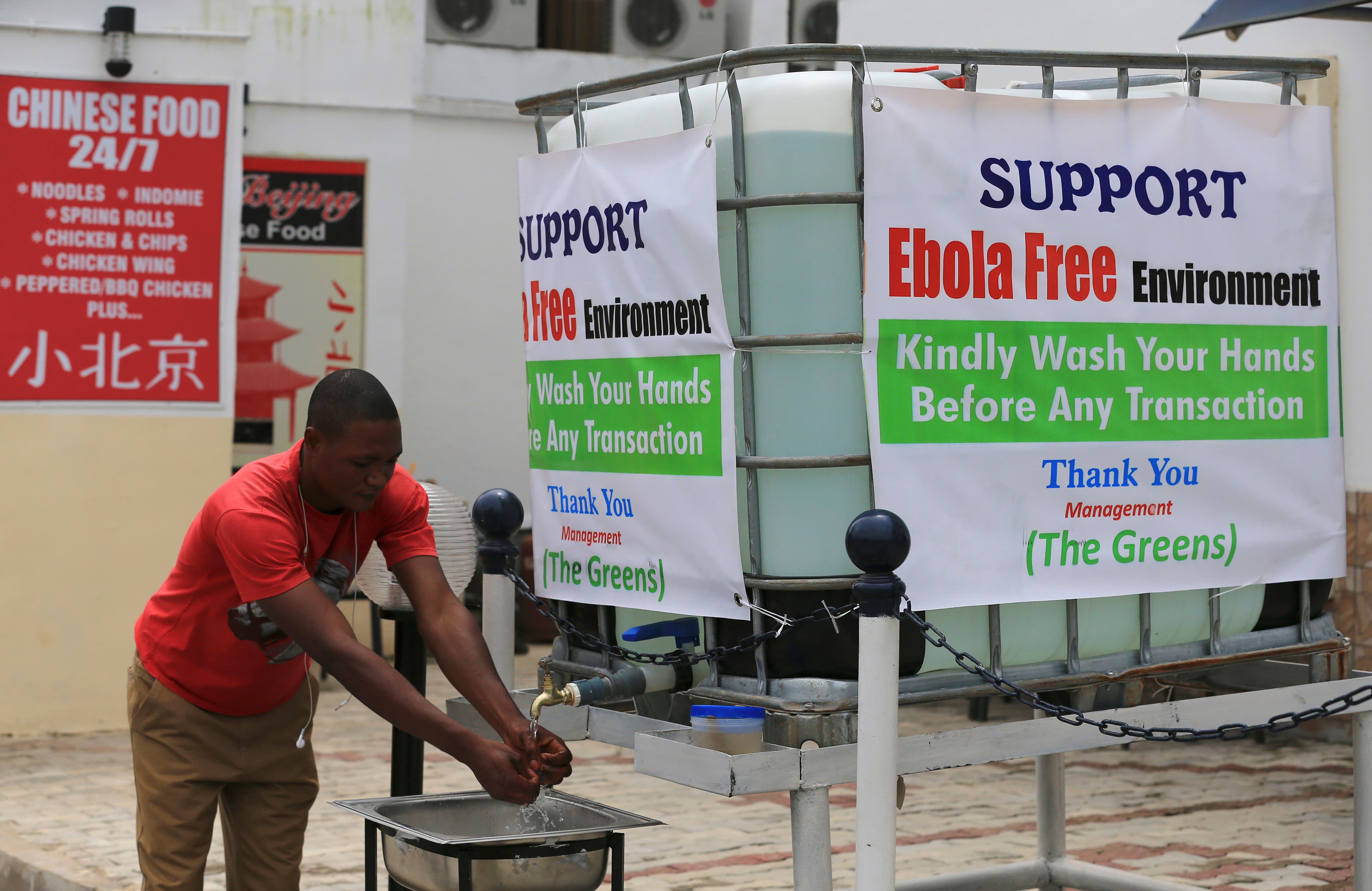 A man washes his hands at a tap outside the Green Pharmacy at Area 8 in Abuja, Nigeria.