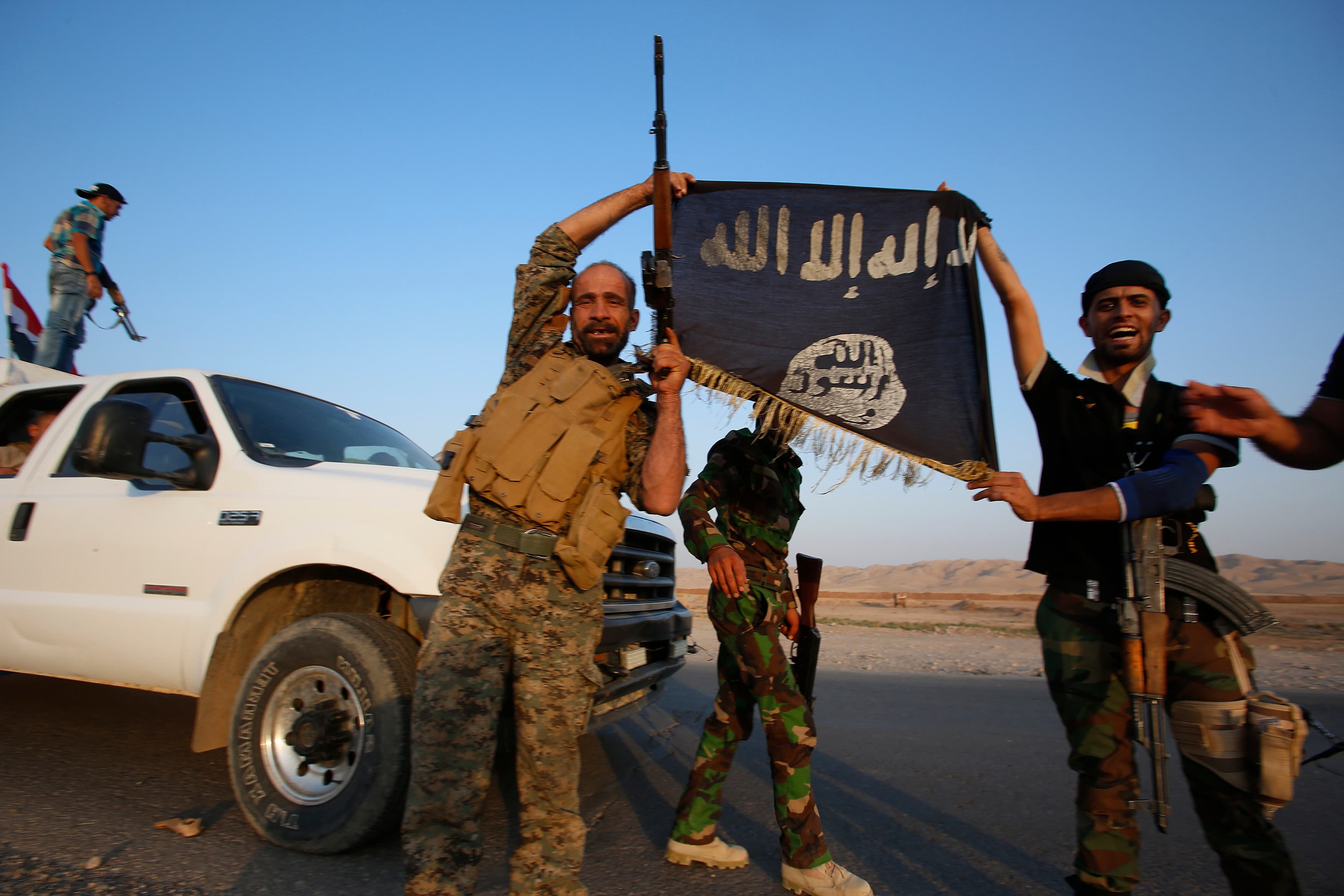 Iraqi Shiite fighters hold the Islamic State flag as a trophy as they celebrate after breaking the siege of Amerli by ISIS militants on September 1, 2014.