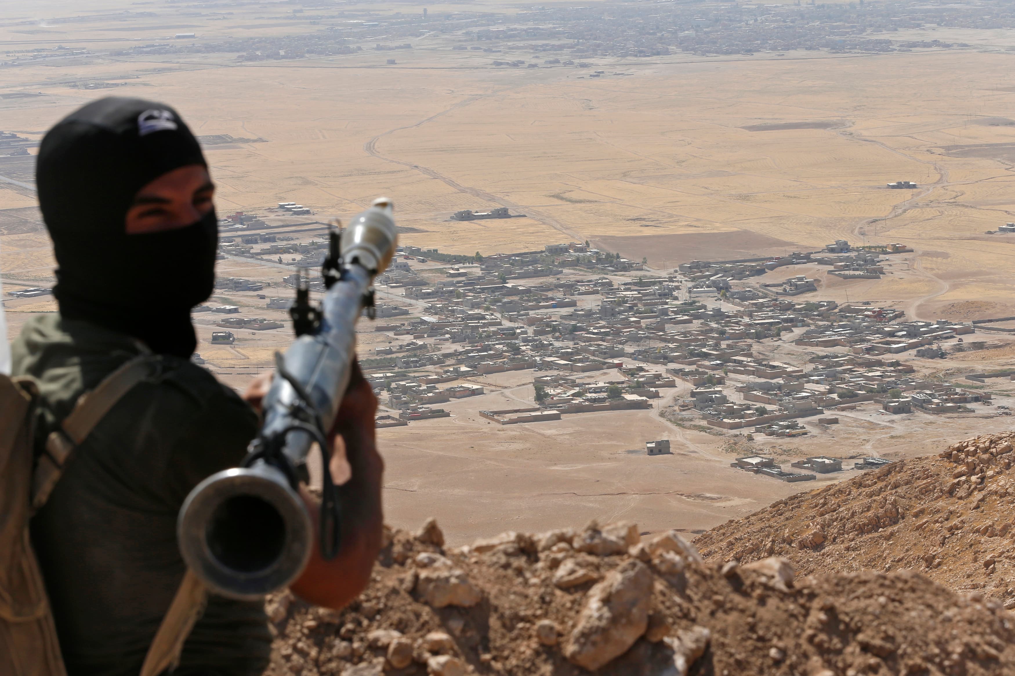 A Kurdish peshmerga fighter holds a rocket-propelled grenade launcher as he takes up position in an area overlooking a village controlled by the Islamic State near Mosul, Iraq.