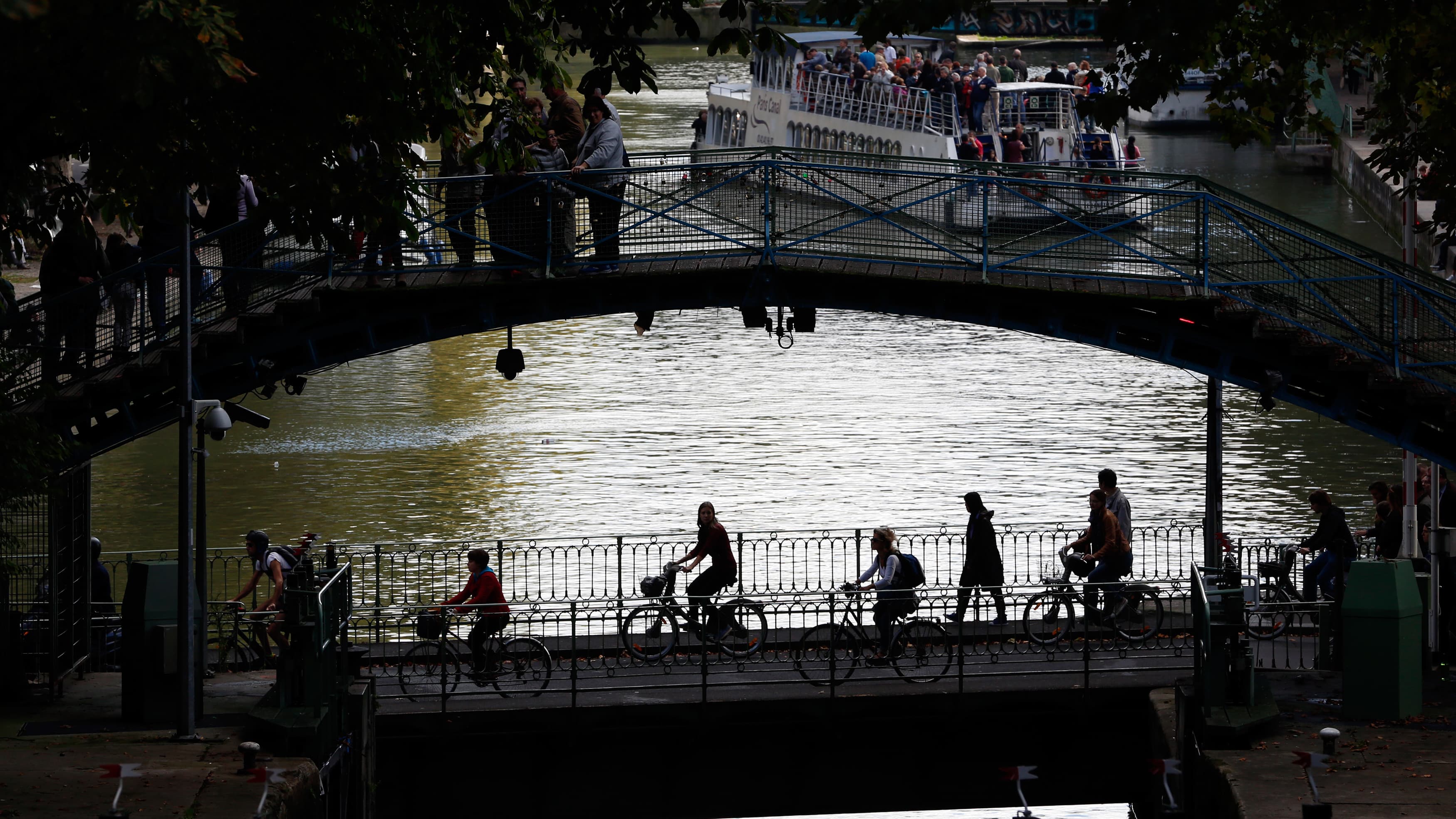 People ride bicycles across the Canal Saint-Martin in Paris, the city’s main canal.
