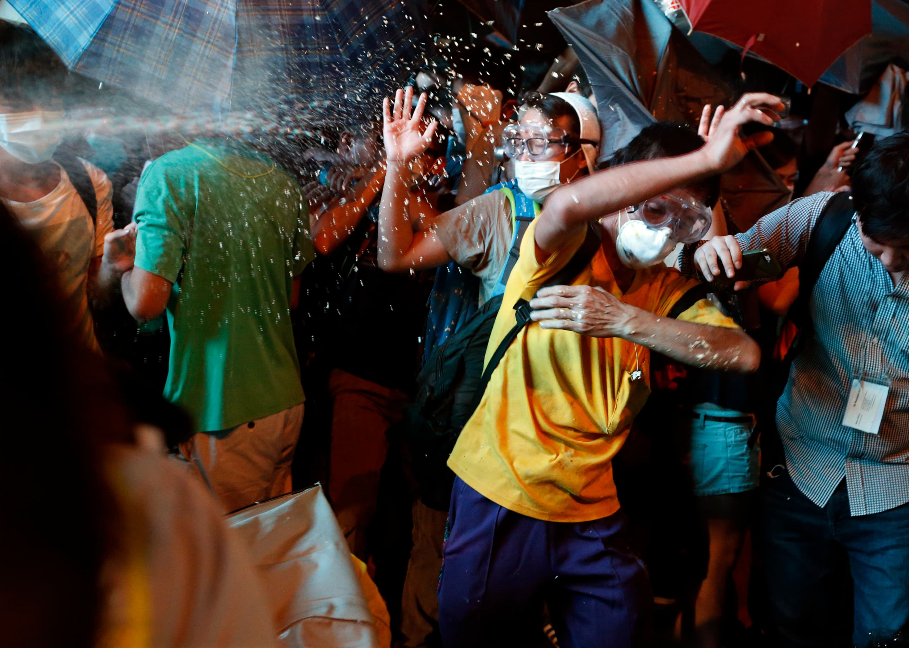 Protesters are pepper sprayed by riot police during a confrontation in the Mong Kok shopping district of Hong Kong on Friday evening.