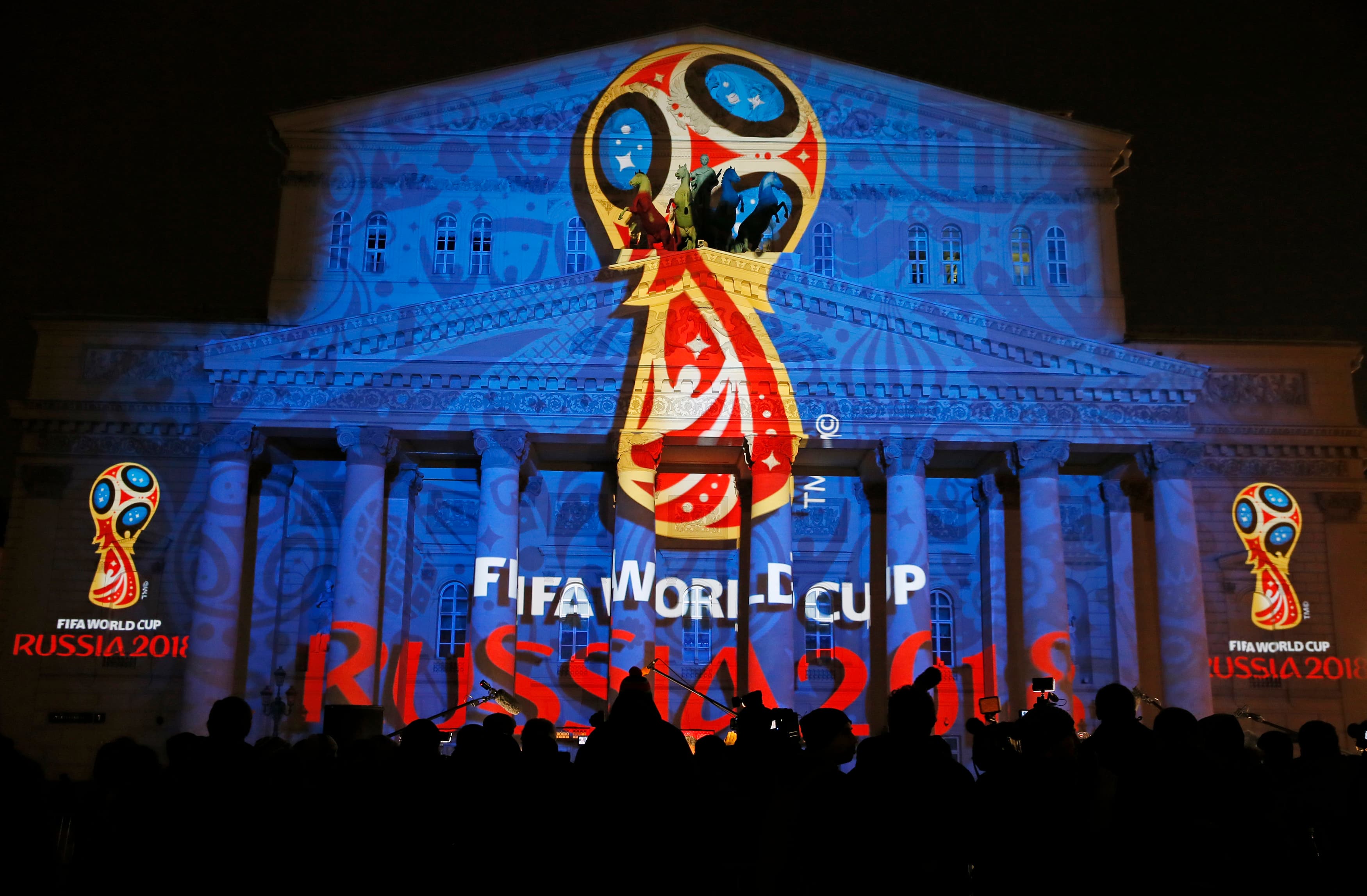 Journalists look at a light installation showing the official logotype of the 2018 FIFA World Cup during its unveiling ceremony at the Bolshoi Theater building in Moscow, October 28, 2014.