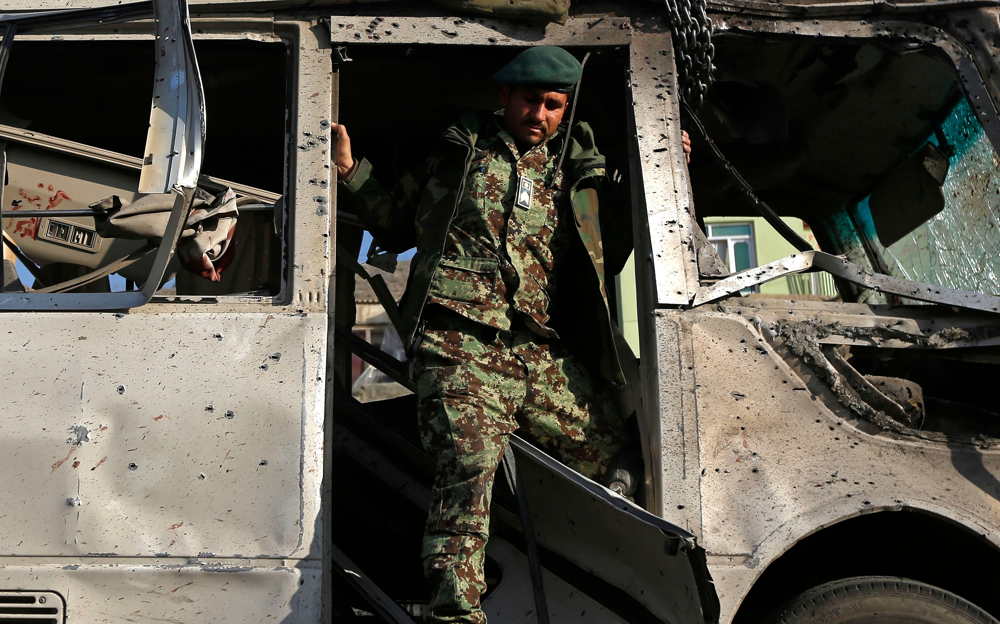 An Afghan soldier inspects the site of a suicide attack in Kabul on December 11, 2014. A suicide bomber targeted a bus carrying Afghan army personnel, killing six soldiers and wounding 11.