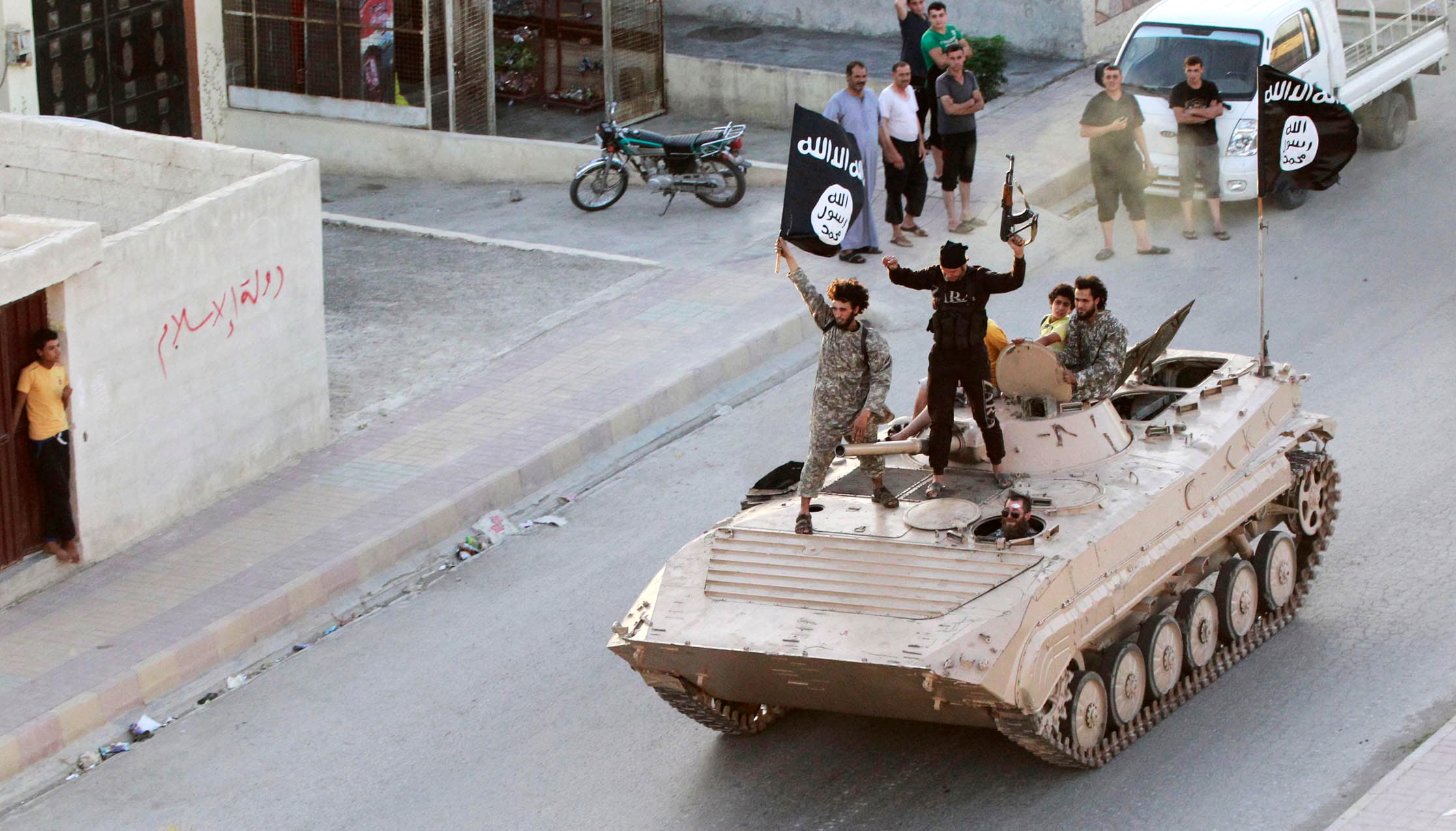 Militant Islamist fighters hold the flag of Islamic State (IS) while taking part in a military parade along the streets of northern Raqqa province in this June 30, 2014 file photo.