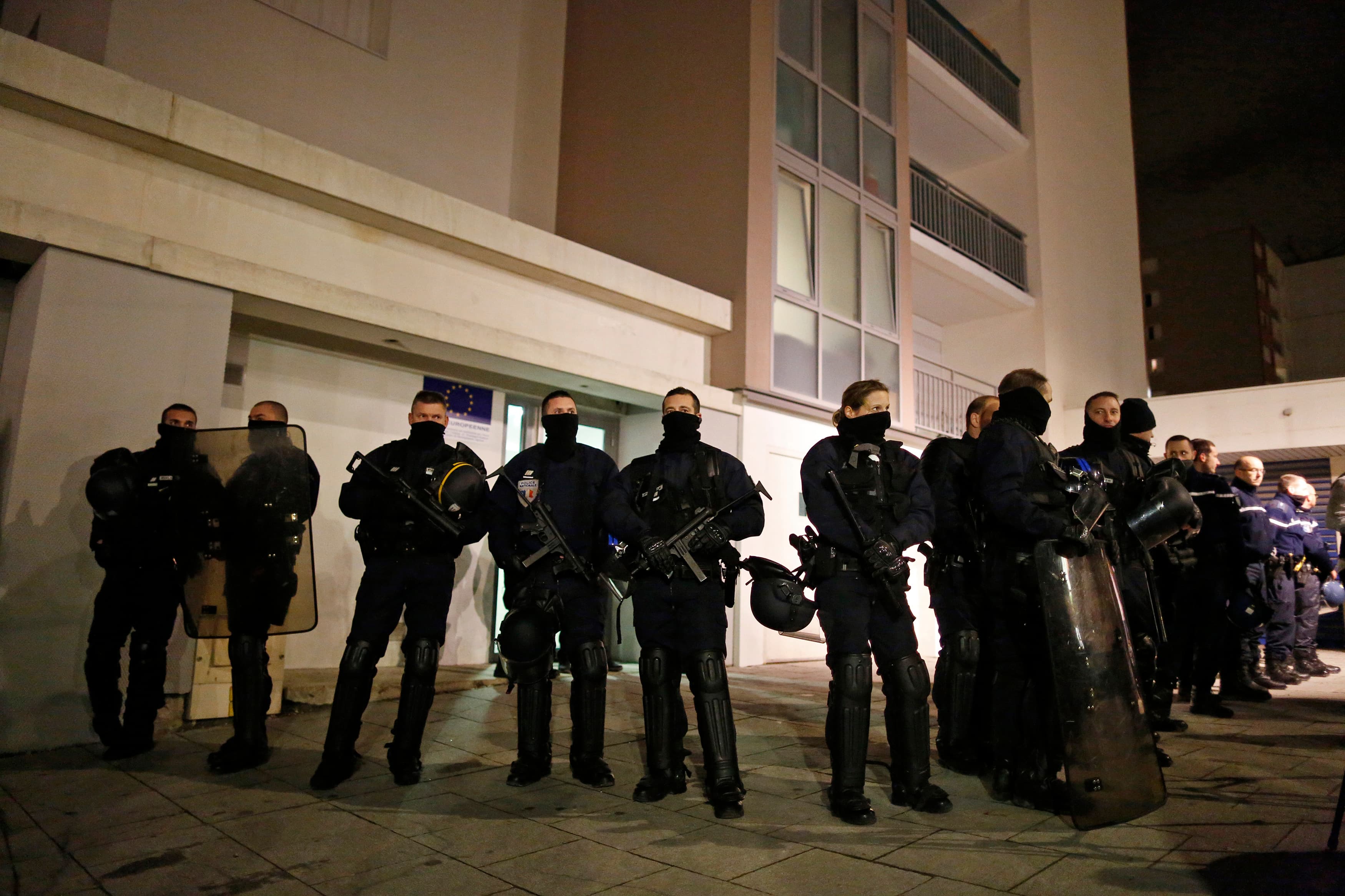 Police officers secure access to a residential building during investigations in the eastern French city of Reims on January 8, 2015, after the shooting against the Paris offices of Charlie Hebdo, a satirical newspaper.
