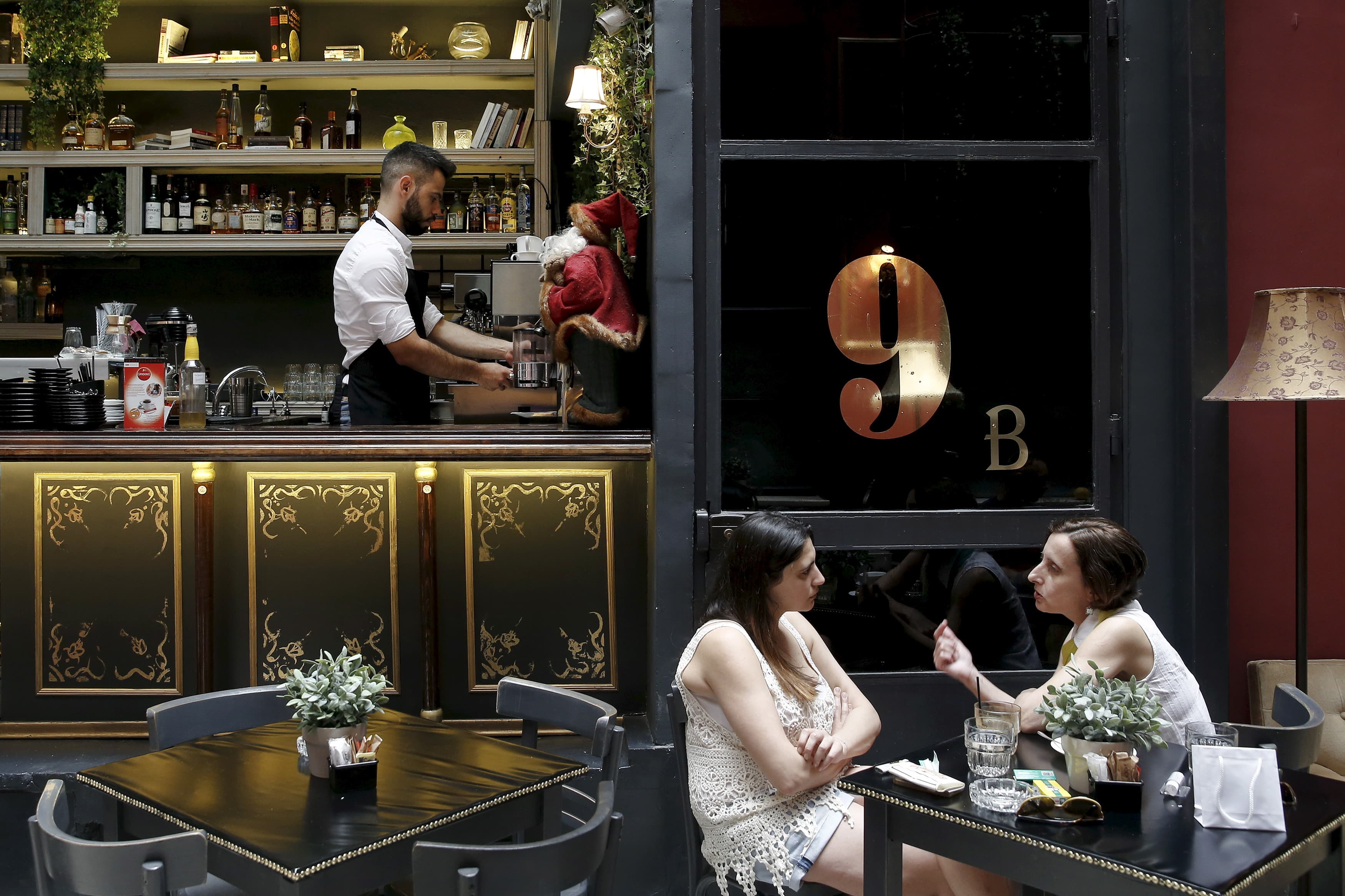 Women talk inside a cafe in Athens