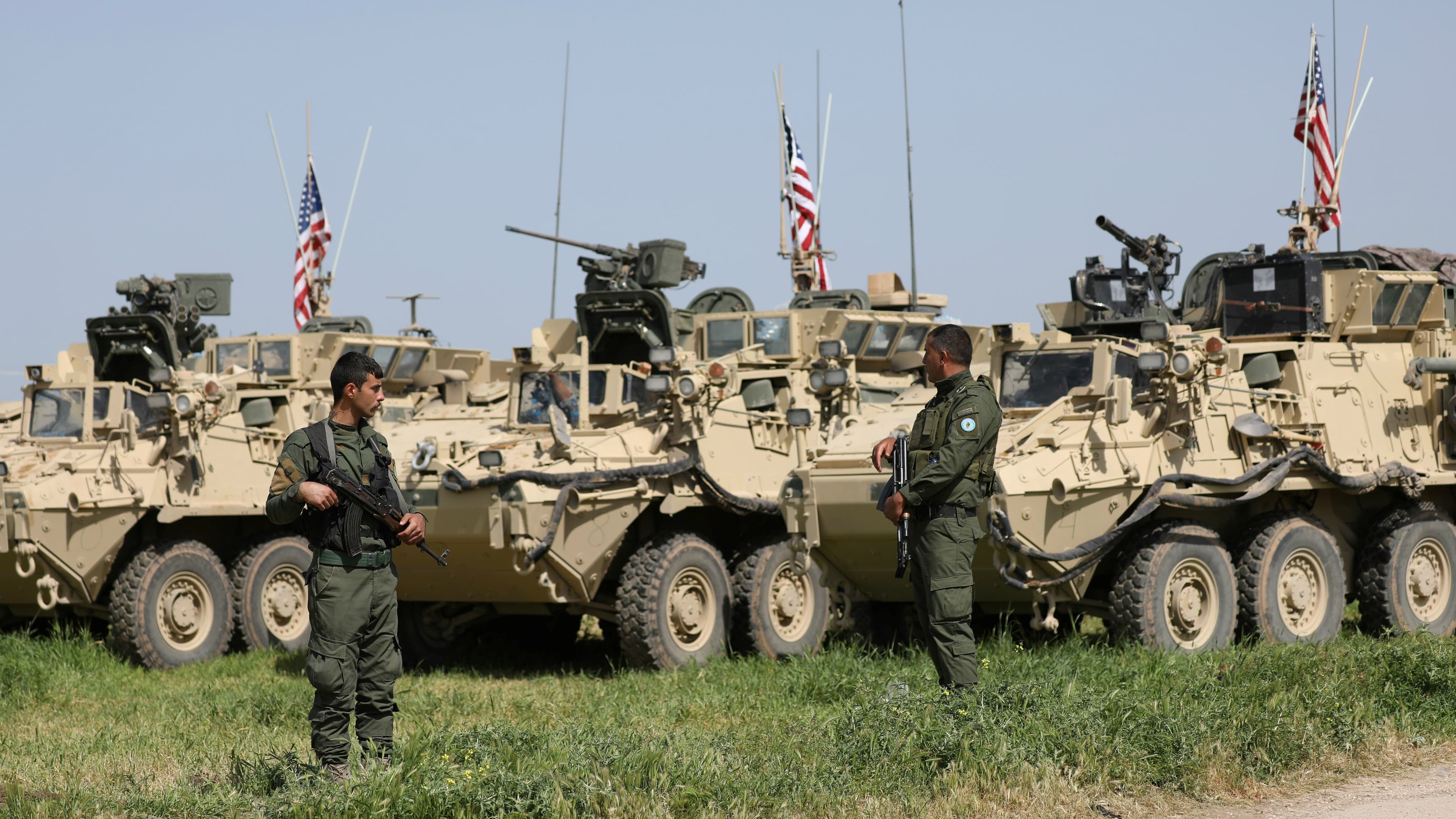 Kurdish fighters from the People's Protection Units (YPG) stand near US military vehicles in the town of Darbasiya next to the Turkish border, Syria, April 29, 201