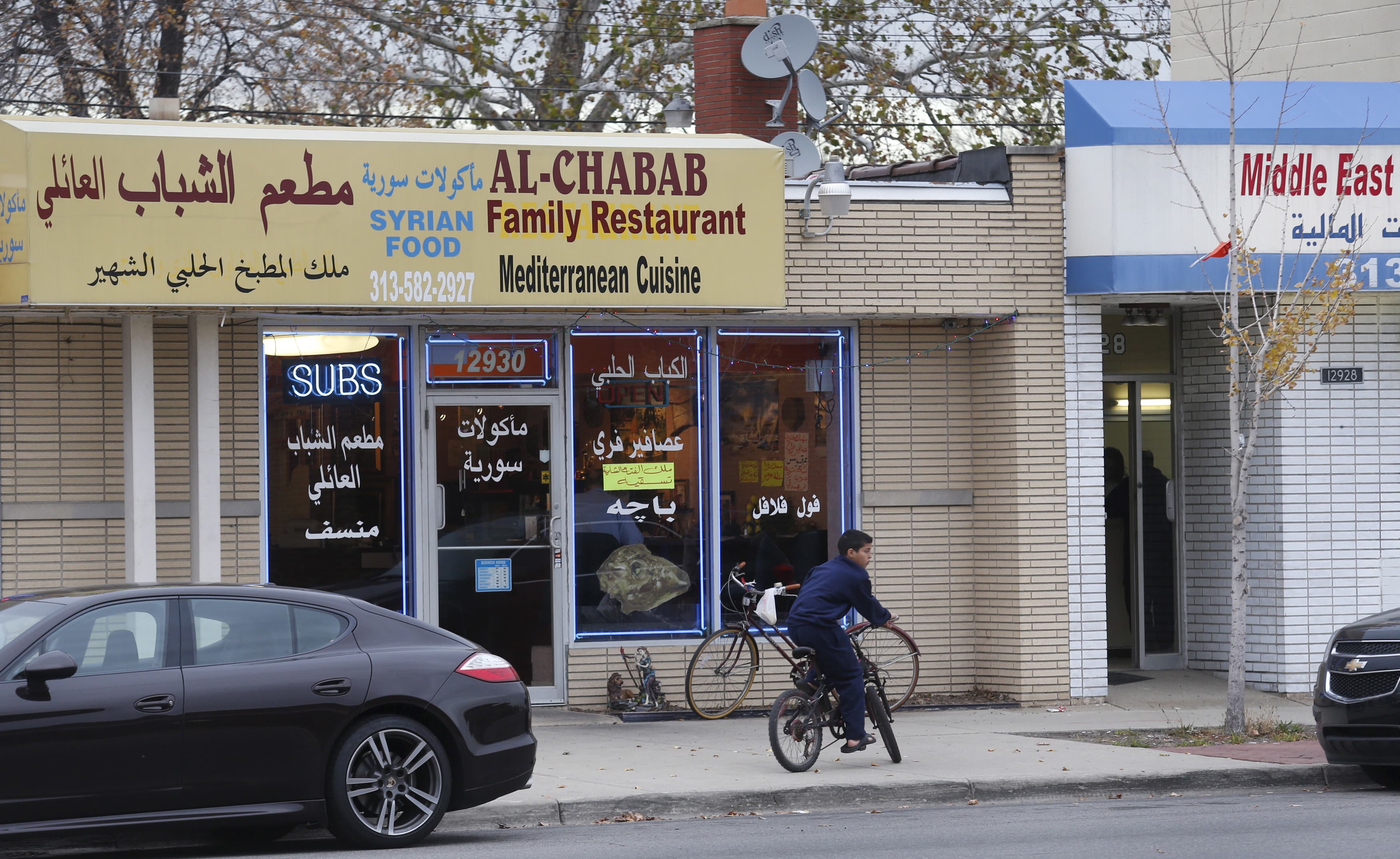 A street with small businesses, young boy on bicycle