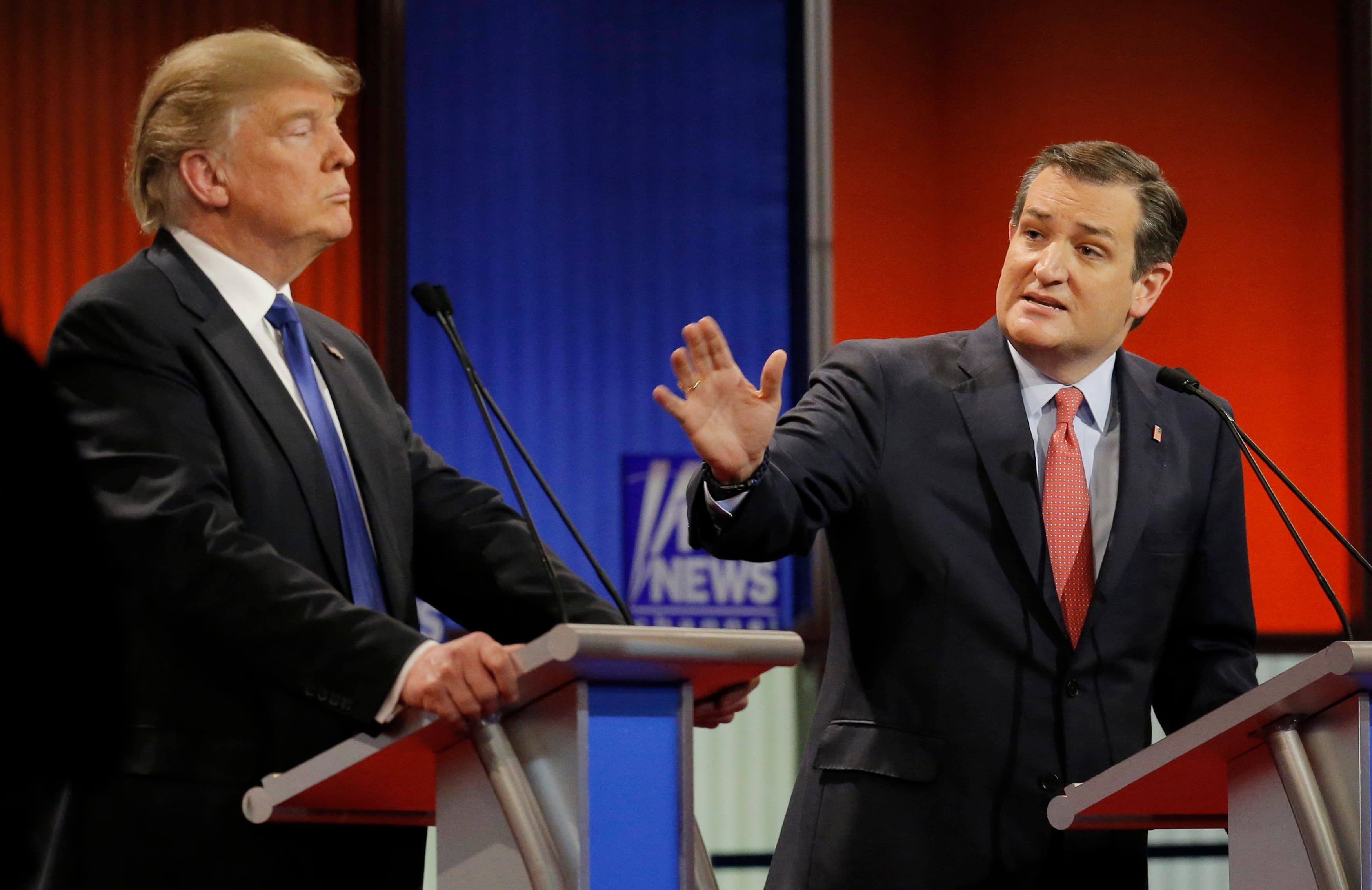 Ted Cruz gestures at Donald Trump from behind debate podiums