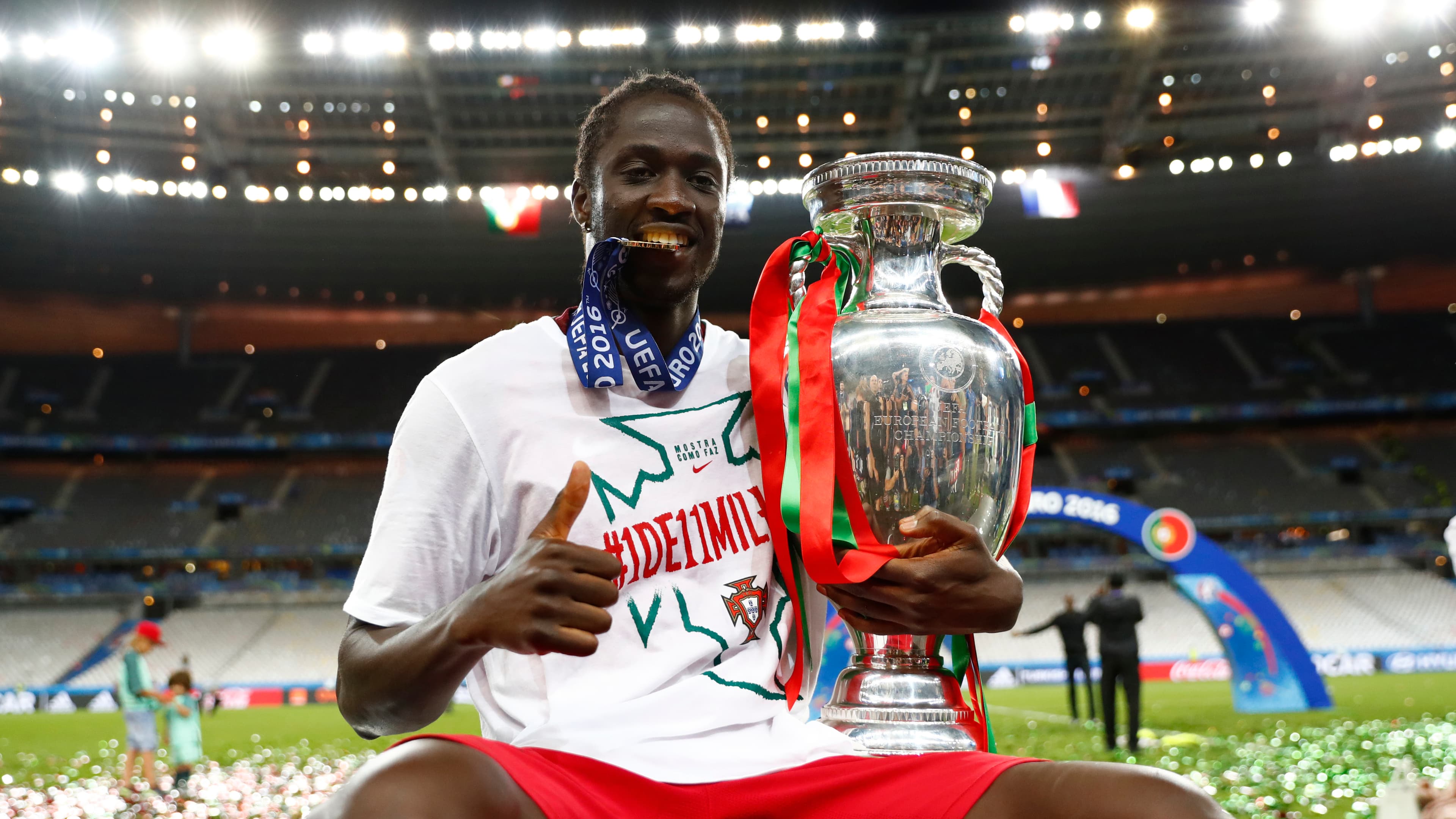Soccer player bites his with a trophy on the field
