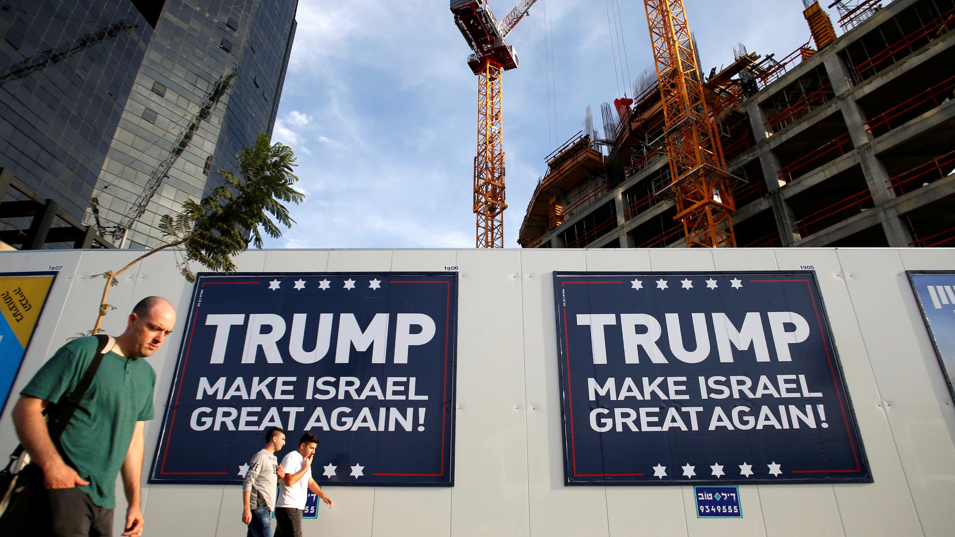 People walk past signs bearing the name of U.S. President-elect Republican Donald Trump in Tel Aviv, Israel on November 14, 2016.