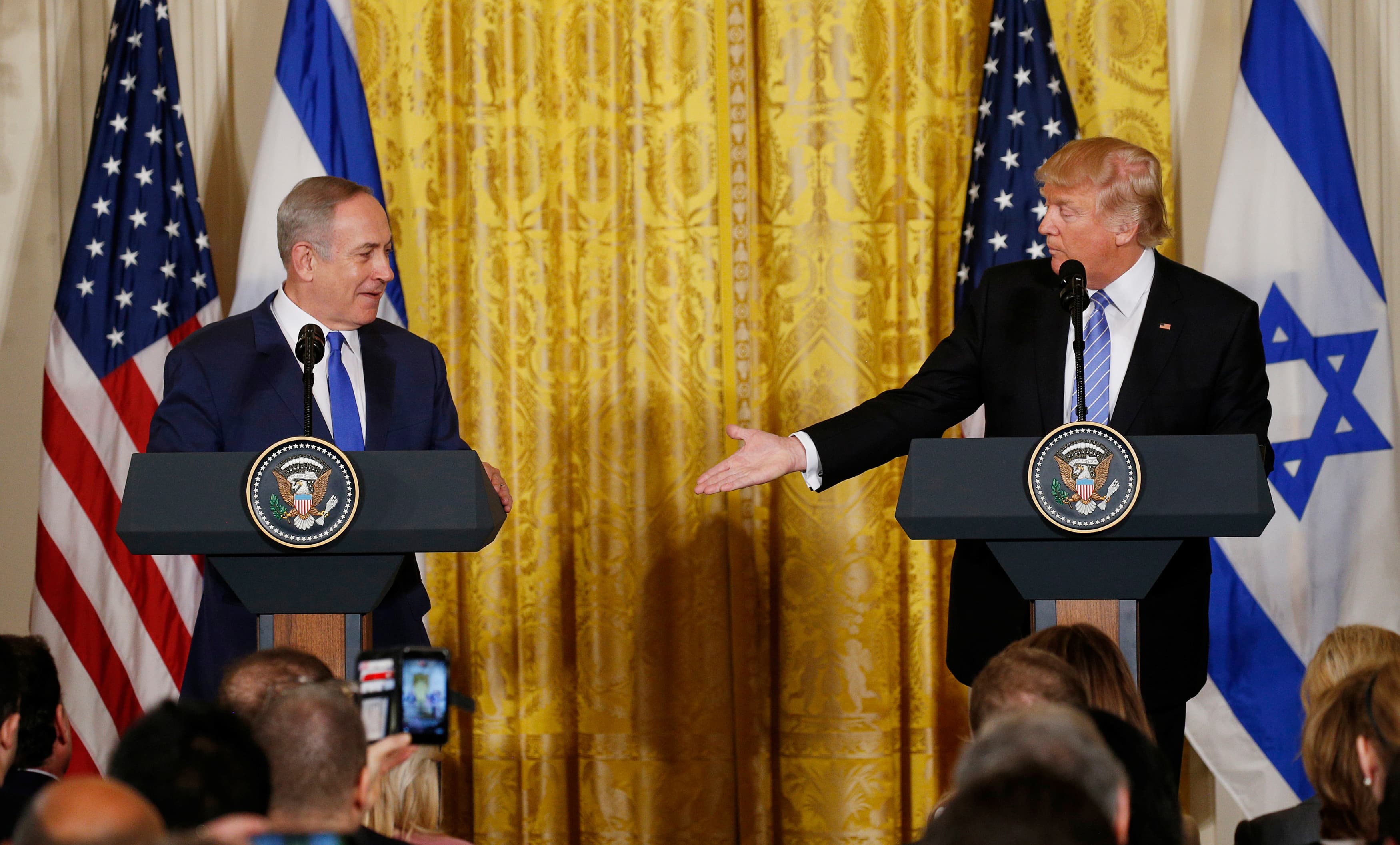 US President Donald Trump (right) reaches to greet Israeli Prime Minister Benjamin Netanyahu after a joint news conference at the White House in Washington, DC, on February 15, 2017.