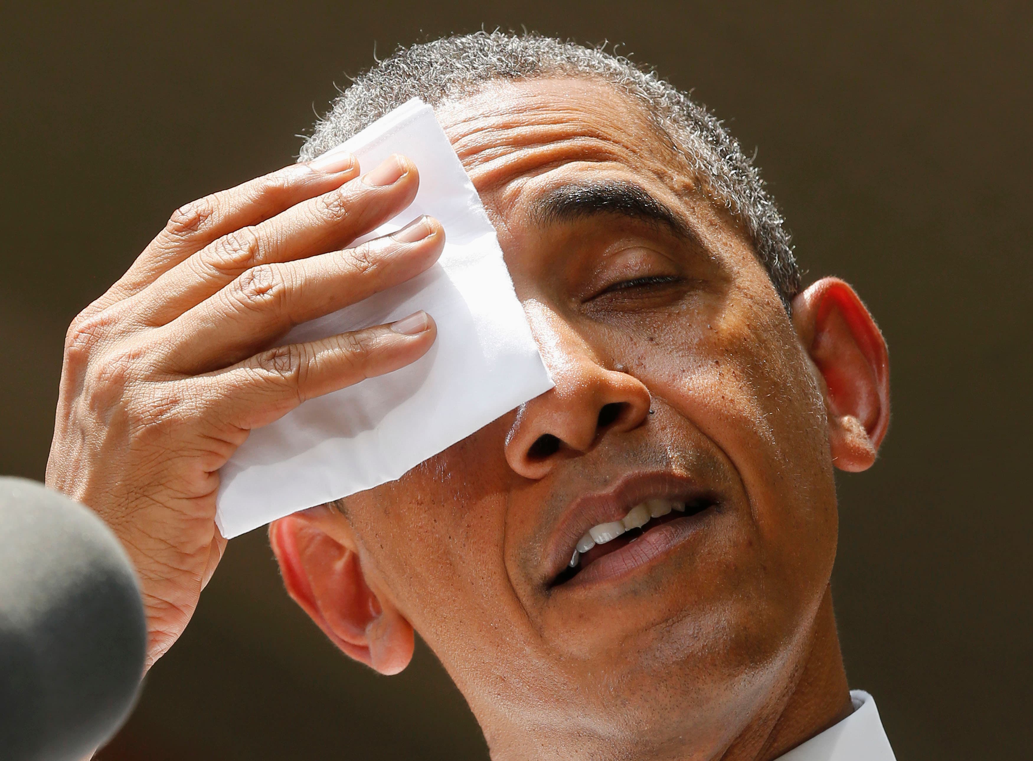 President Barack Obama pauses and wipes his forehead as he speaks about his vision to reduce carbon pollution while preparing the country for the impacts of climate change, at Georgetown University in Washington, June 25, 2013.