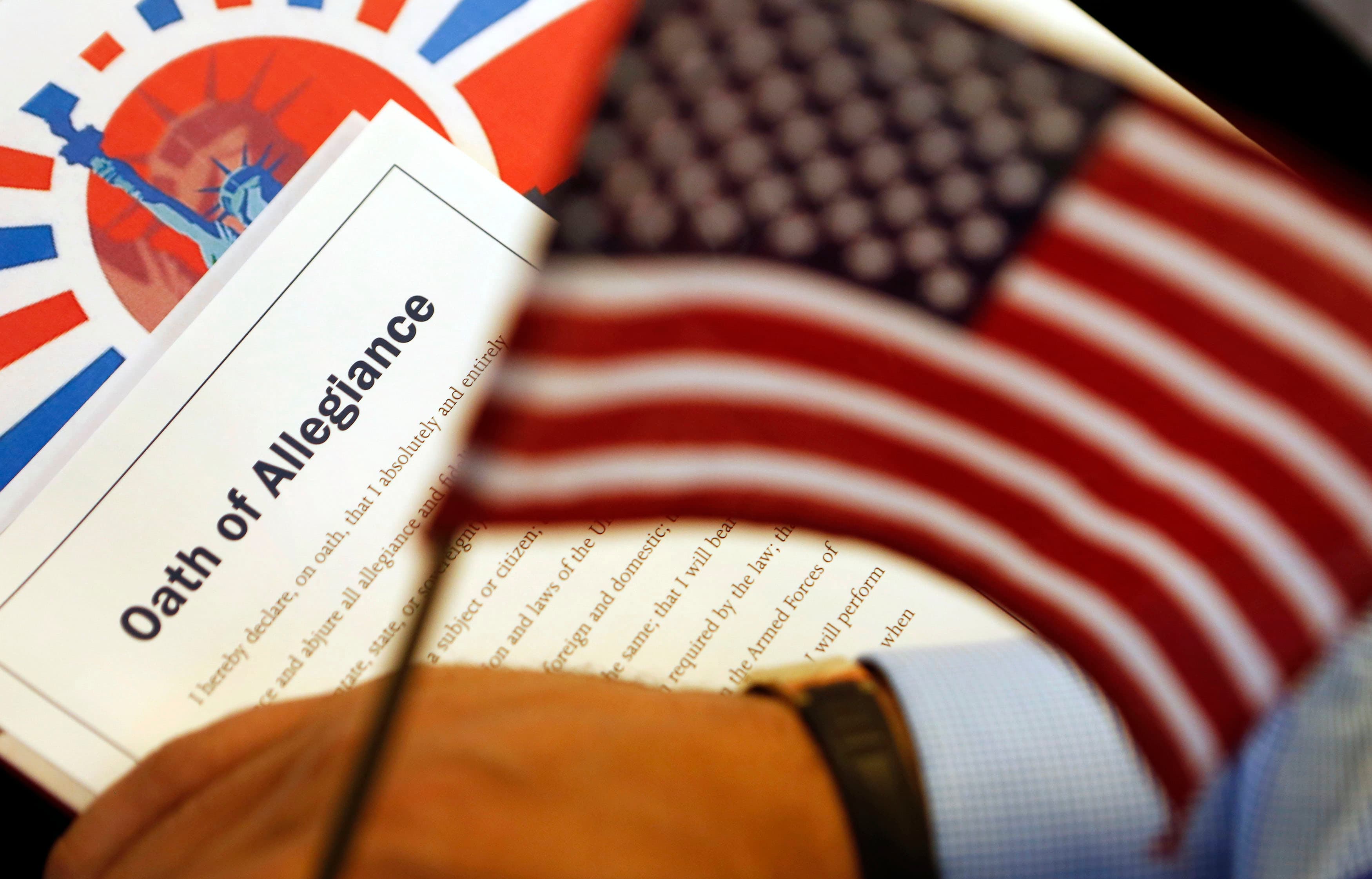 The Oath of Allegiance is held next to an American flag during a naturalization ceremony for citizen candidates in Washington, DC, on July 3, 2013.