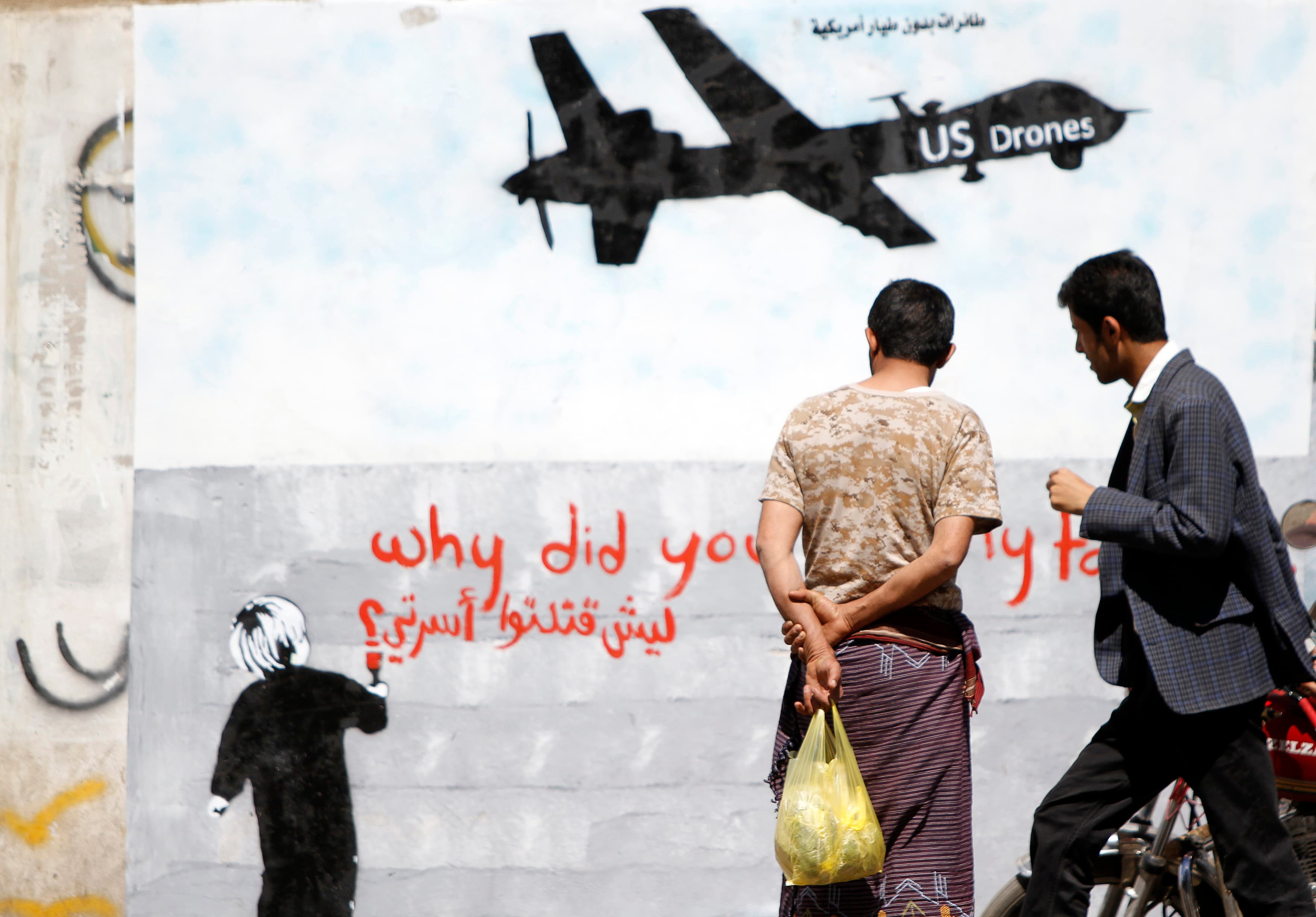 Men look at wall graffiti depicting a American drone along a street in Sana'a, Yemen, on November 9, 2013.