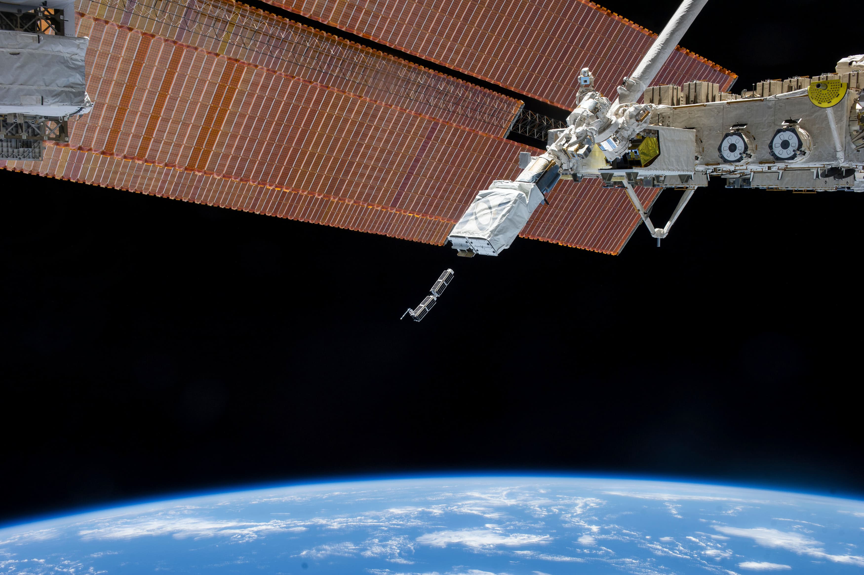 A robotic arm holds a CubeSat