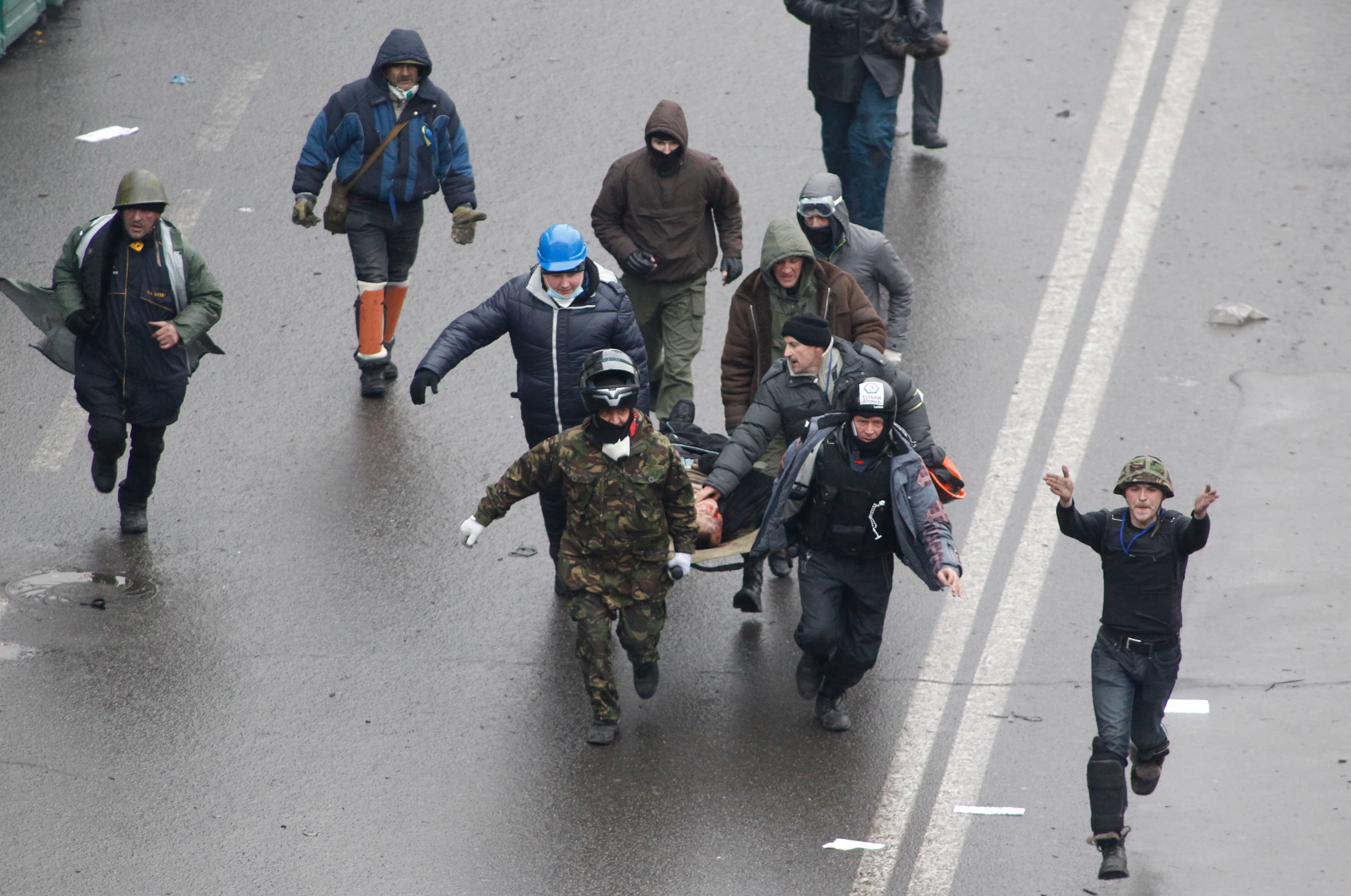 Anti-government protesters run with an injured man on a stretcher in downtown Kiev, February 20, 2014.