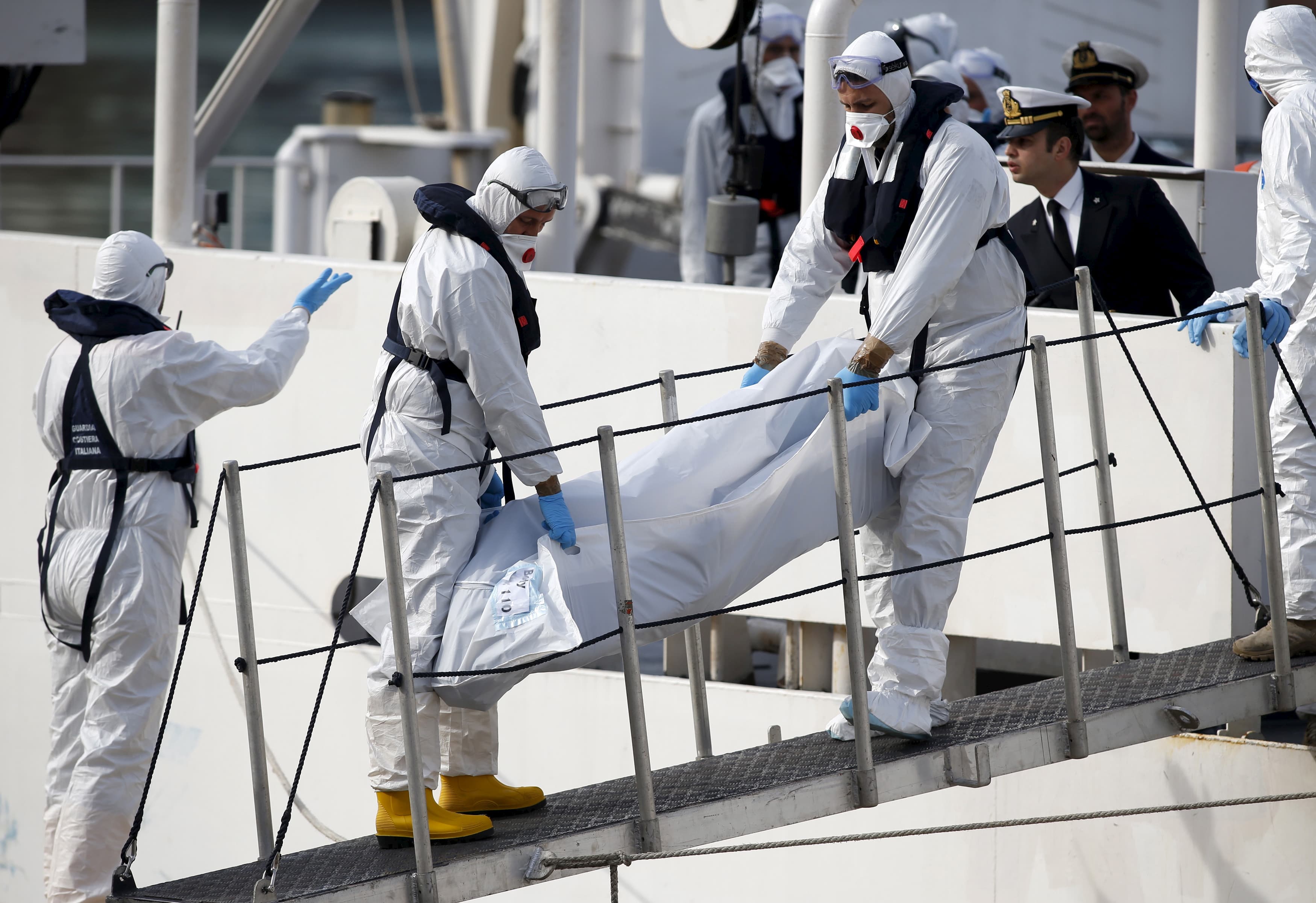 Italian coastguard personnel in protective clothing carry the body of a dead immigrant off their ship, Bruno Gregoretti, in the Grand Harbor of Valletta, Malta, on April 20, 2015.