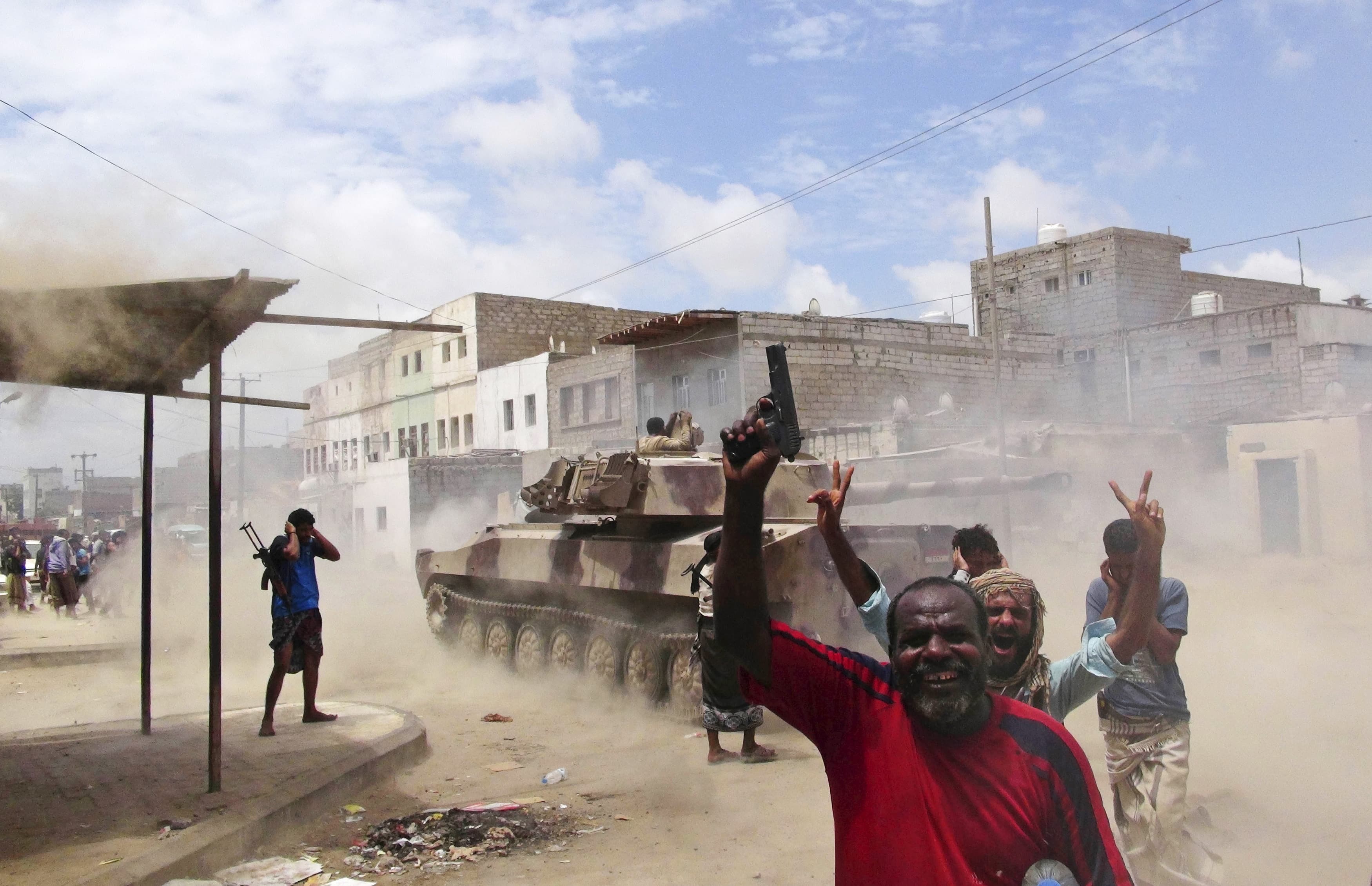 Southern Popular Resistance fighters react as one of their tanks fire at a Houthi position during fighting in Yemen's southern city of Aden