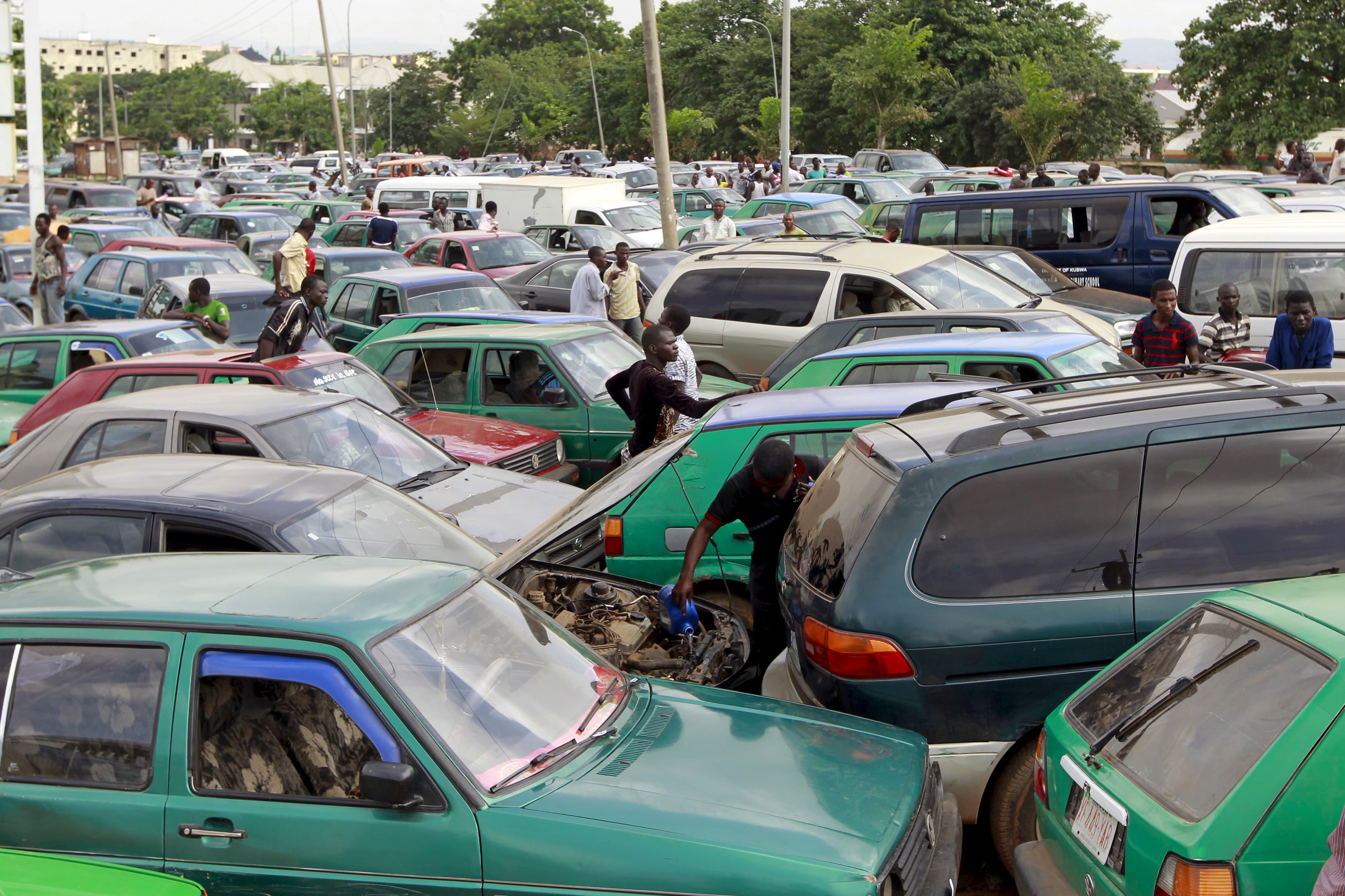 A man works on the engine of his car, as motorists wait for fuel at a gas station in Abuja.