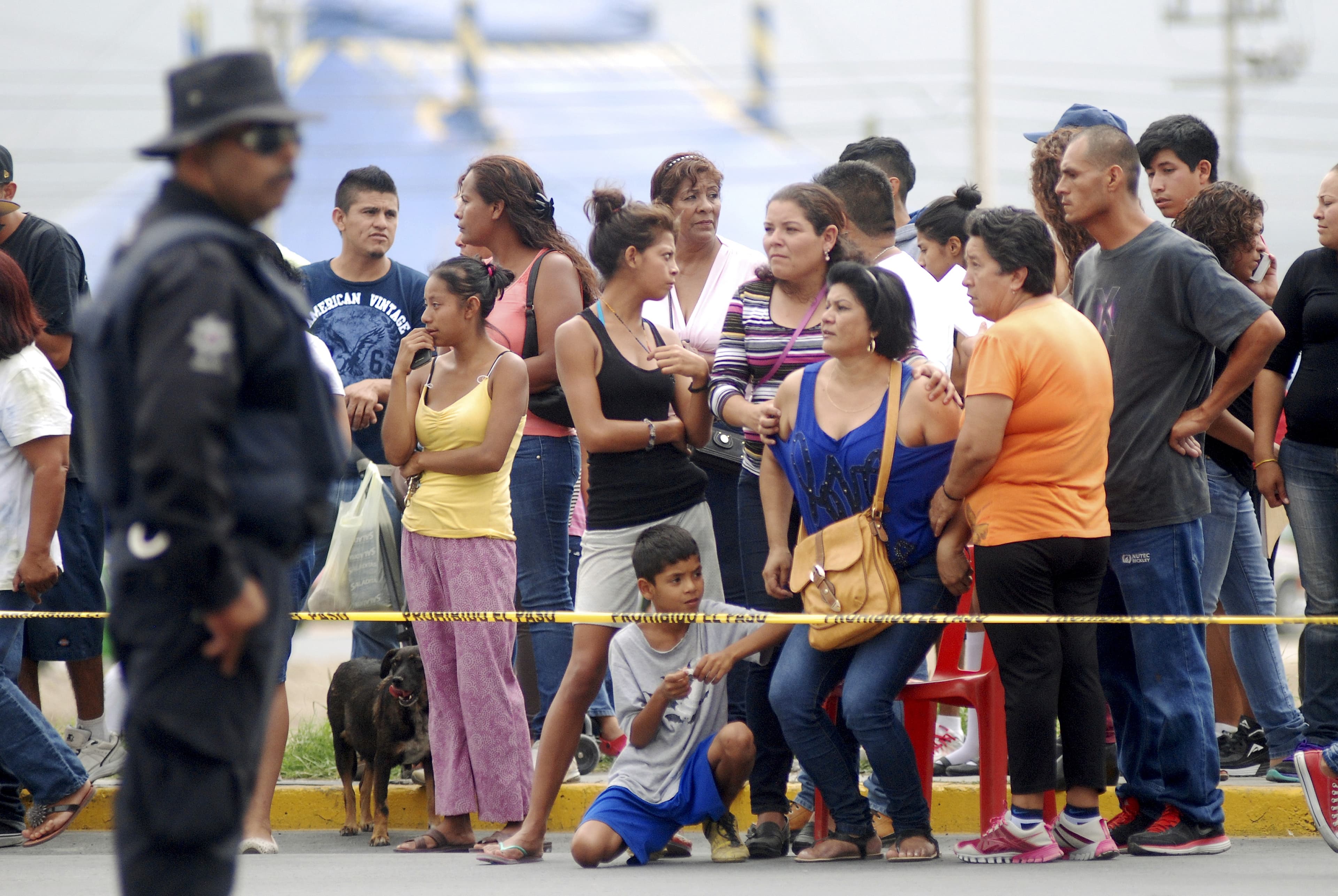 Onlookers stand behind a police cordon as a policeman stands guard at a crime scene in Garcia, on the outskirts of Monterrey, Mexico.