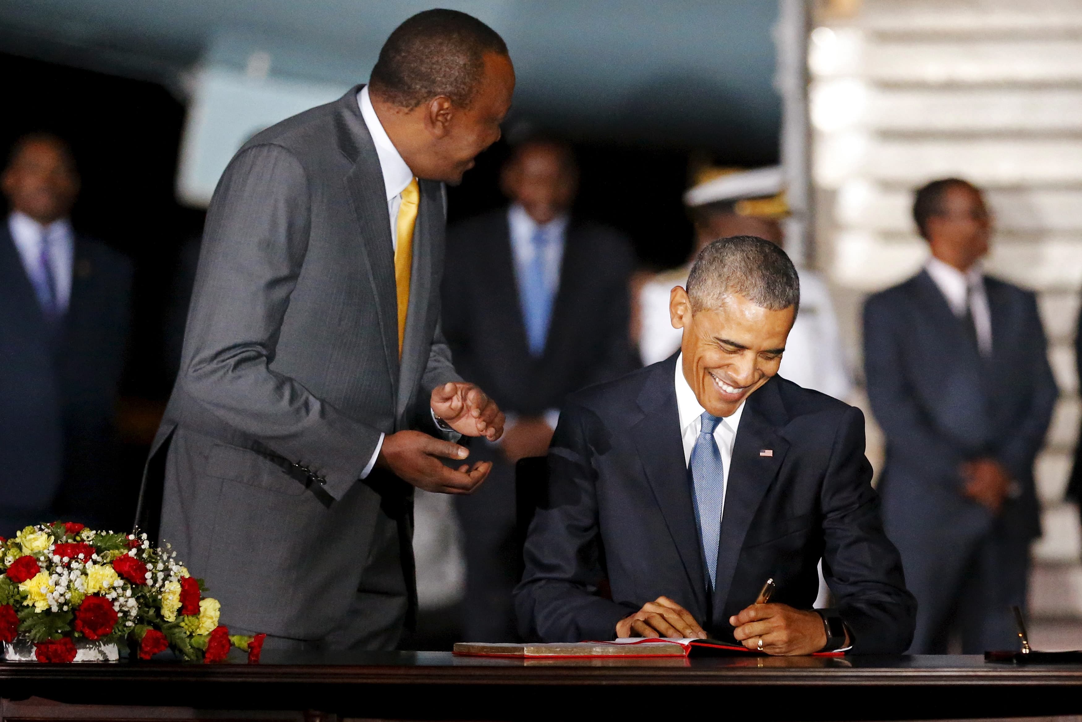 Kenya's President Uhuru Kenyatta (L) looks on as U.S. President Barack Obama signs a guest book as he arrives aboard Air Force One at Jomo Kenyatta International Airport in Nairobi July 24, 2015.