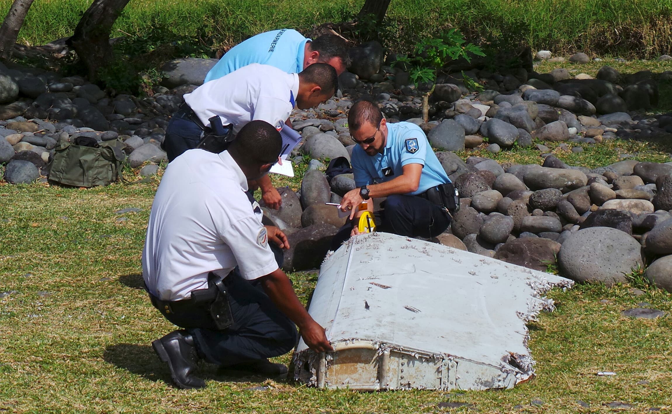 French gendarmes and police inspect a piece of plane debris found on a beach on the French Indian Ocean island of La Reunion.